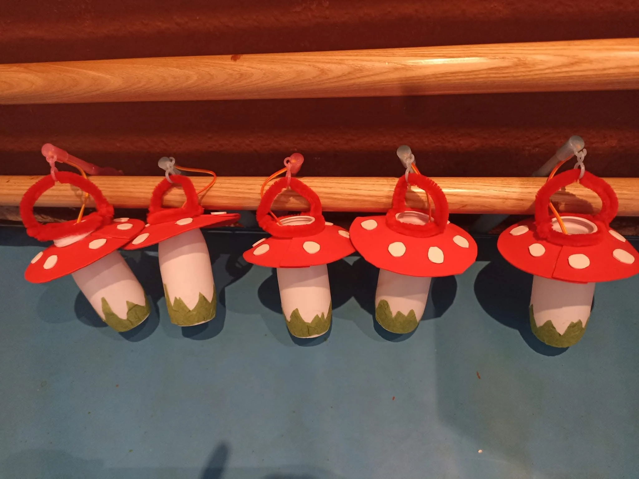 Five decorative mushroom-shaped ornaments hanging from a wooden beam.