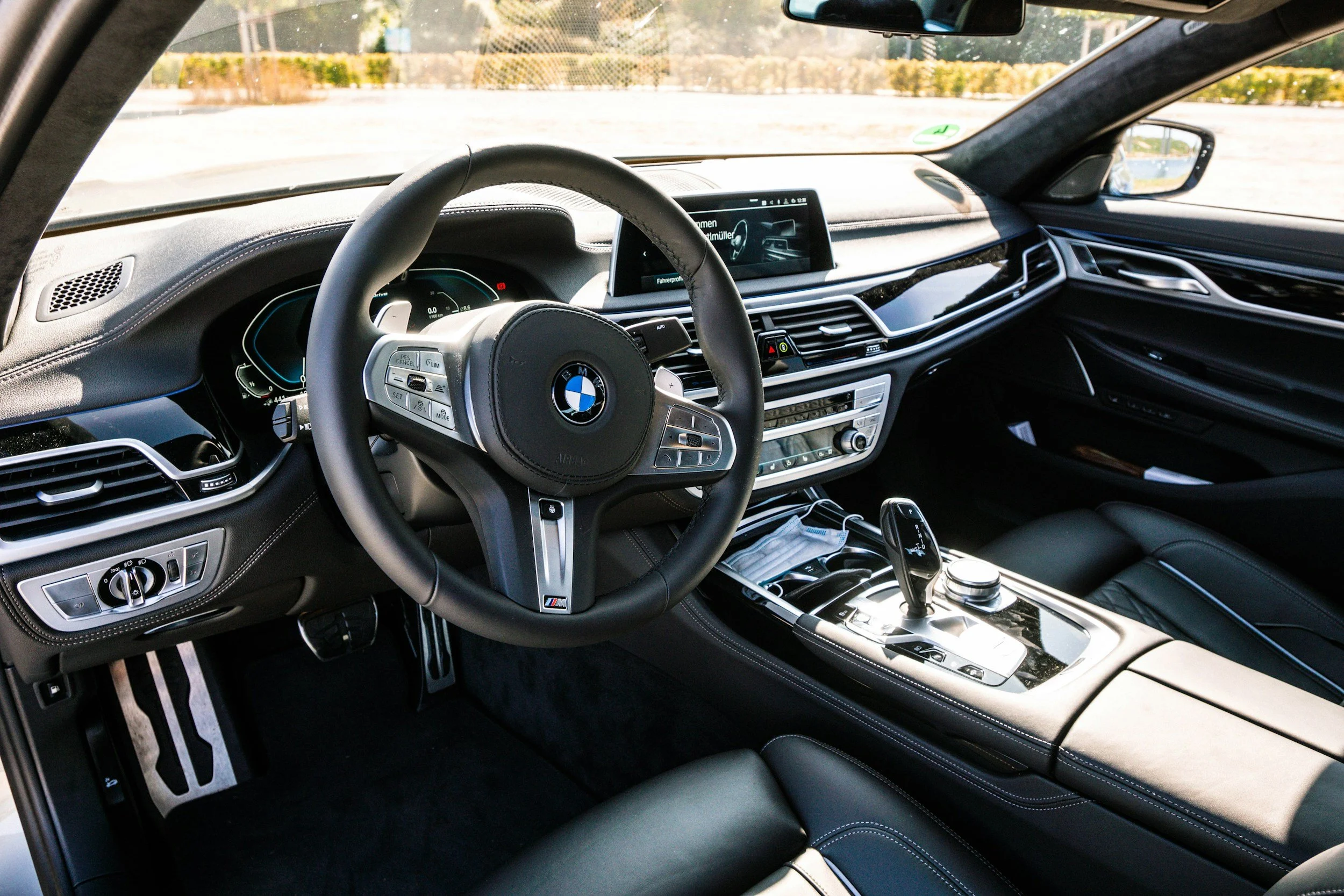 Interior of a BMW car, showing the steering wheel, dashboard, and center console with gear shift and control knobs.