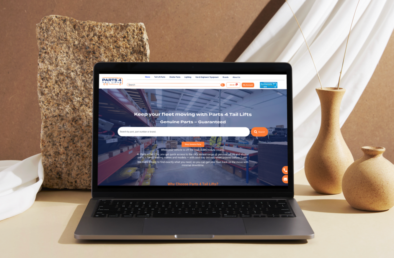 Laptop on a table displaying Part 4 Tail Lifts website, with a large stone and two beige vases nearby.