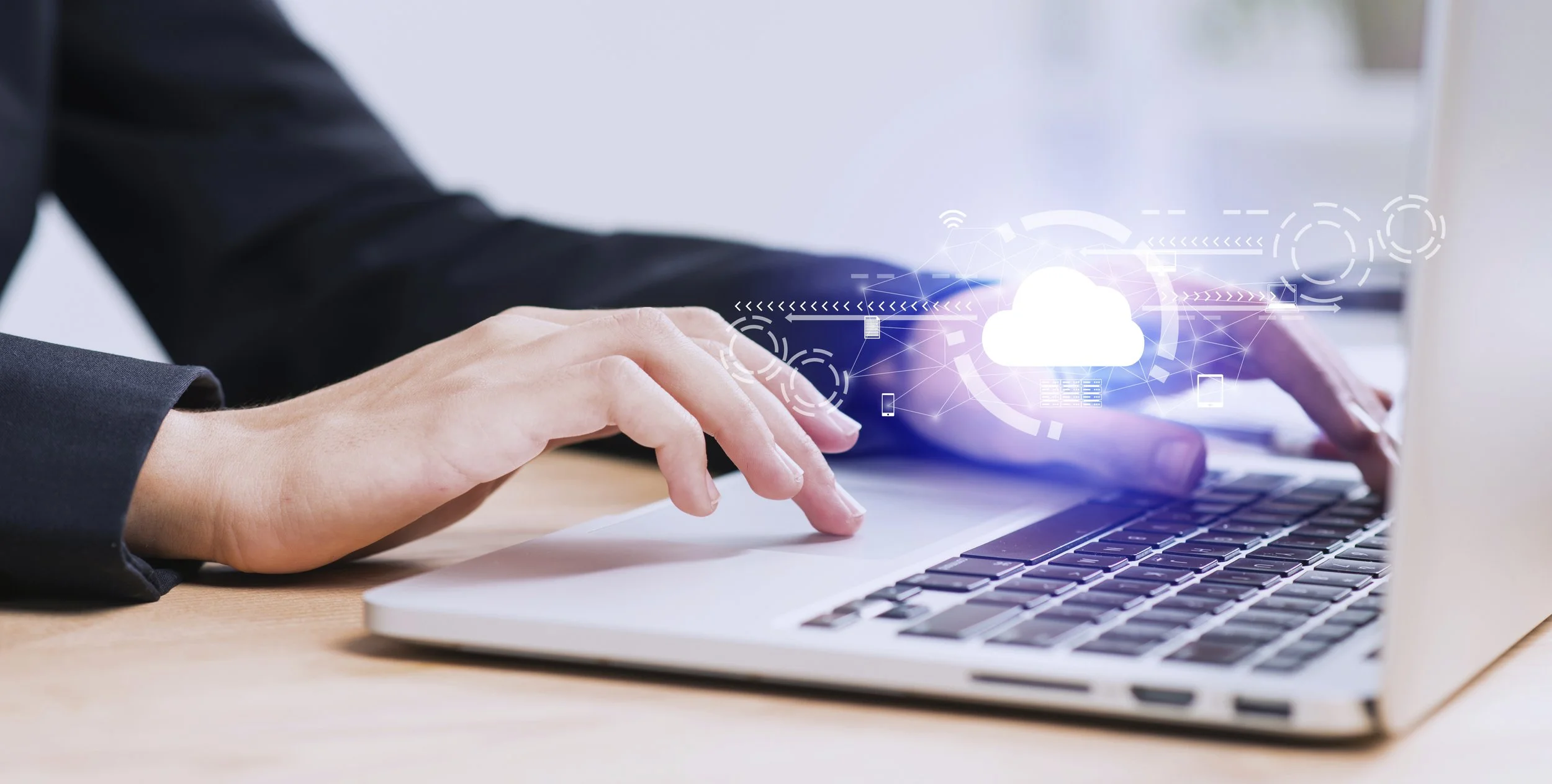 Main d'une personne tapant sur un clavier d'ordinateur portable avec un graphique de nuage cloud en surimpression, représentant le stockage ou le transfert de données dans le cloud.