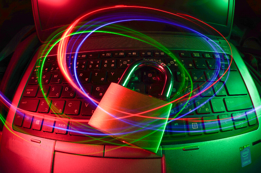 Clavier d'ordinateur avec un cadenas en métal et des traînées de lumière colorées en forme de cœurs autour.