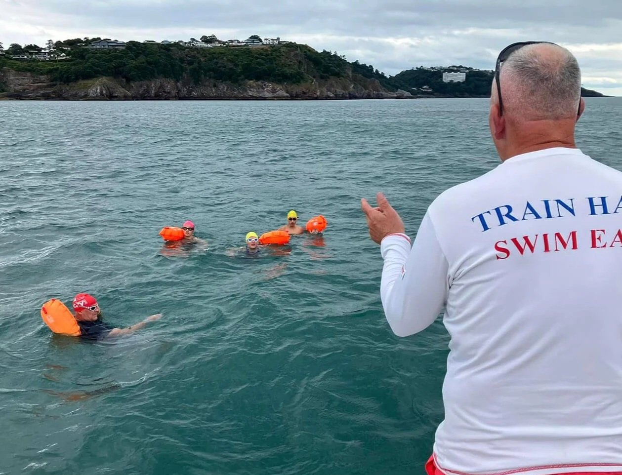 Coach cheering on four swimmers in the sea