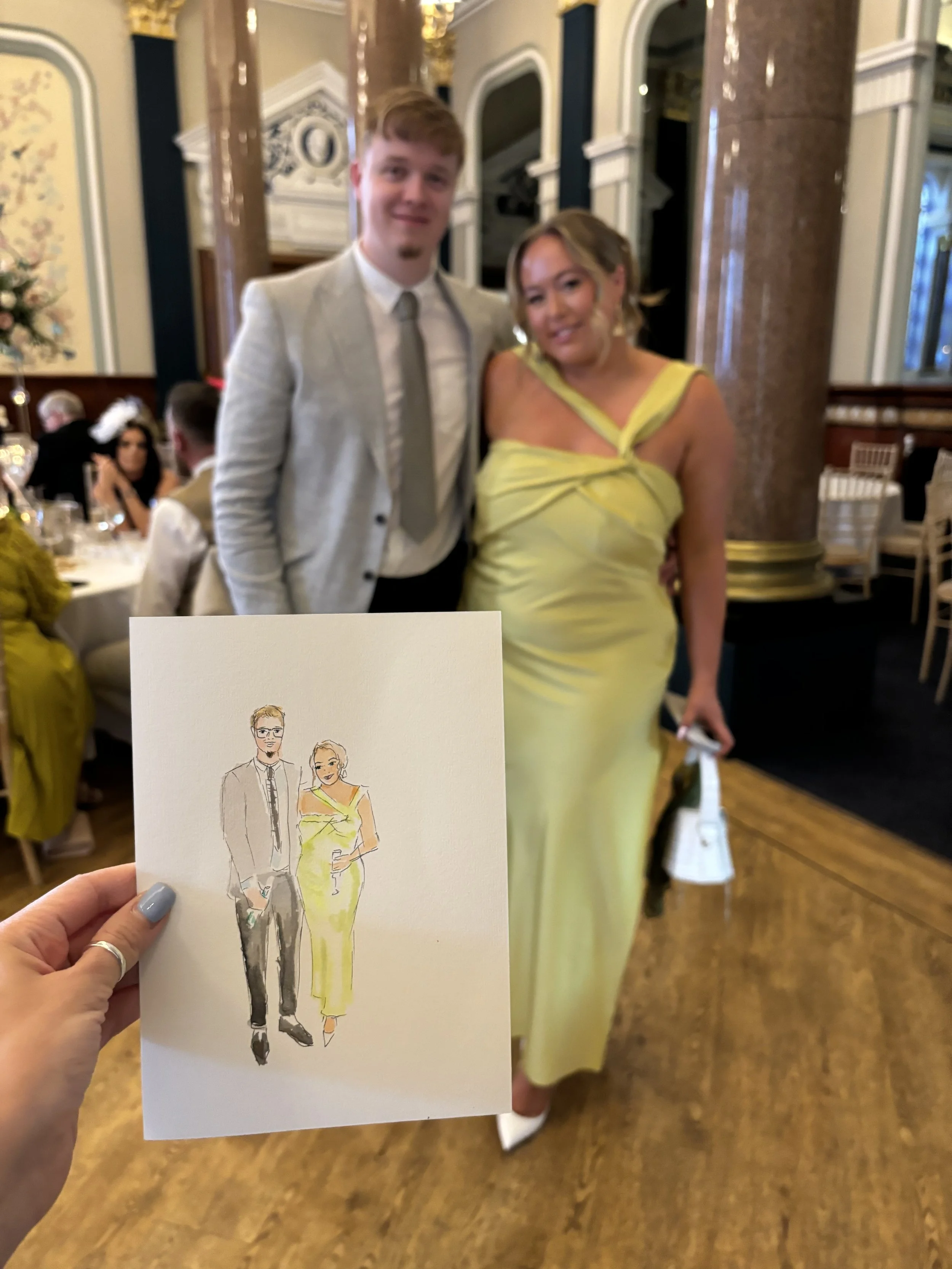 A woman in a yellow dress and a man in a light suit are seen in the background at what appears to be a formal event. The photo is blurred, but it shows a decorated indoor setting with other guests seated at tables.