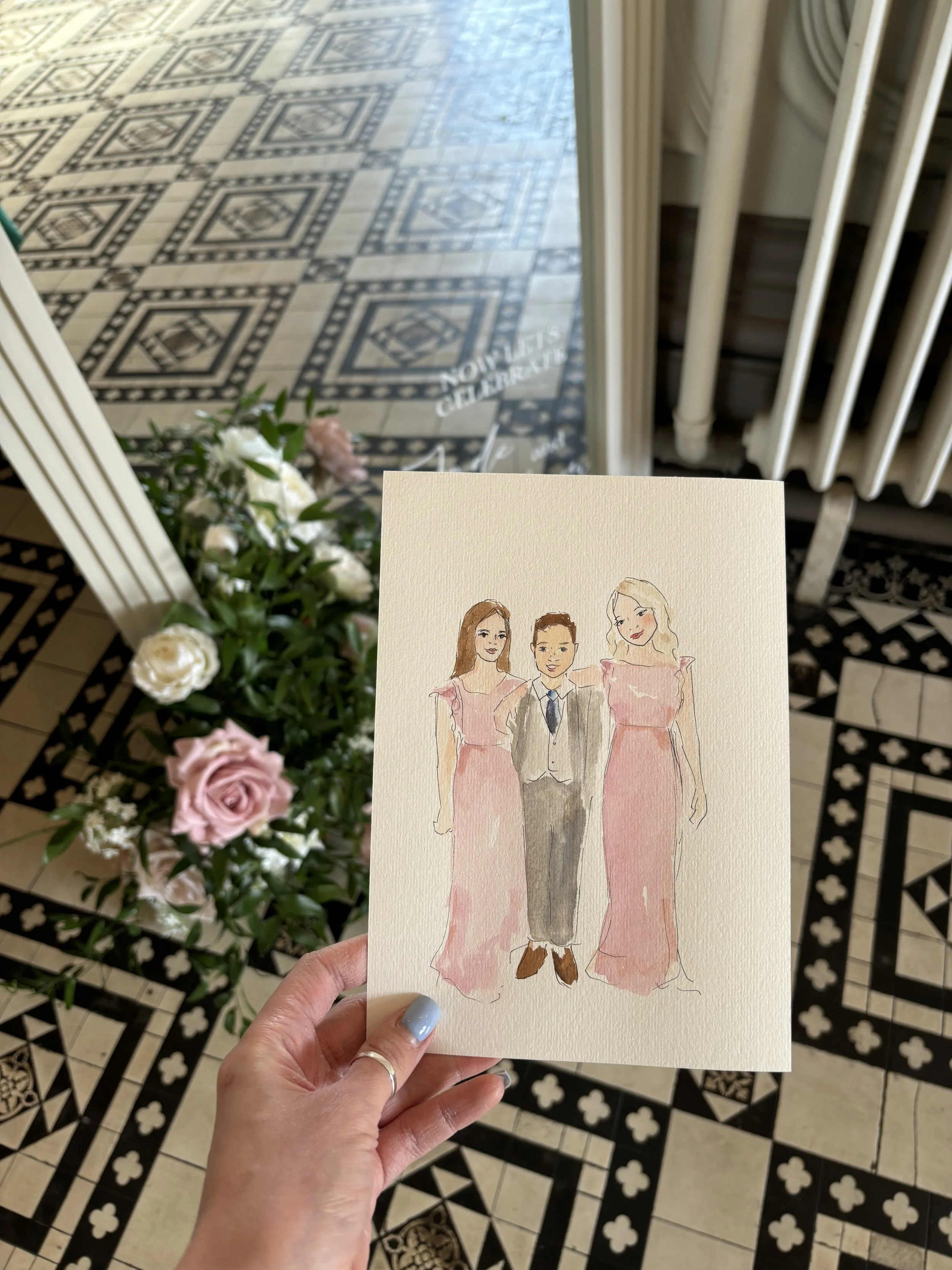 A hand holding a watercolor drawing of two women and one man dressed in formal attire, with a bouquet of flowers and a tiled floor in the background.