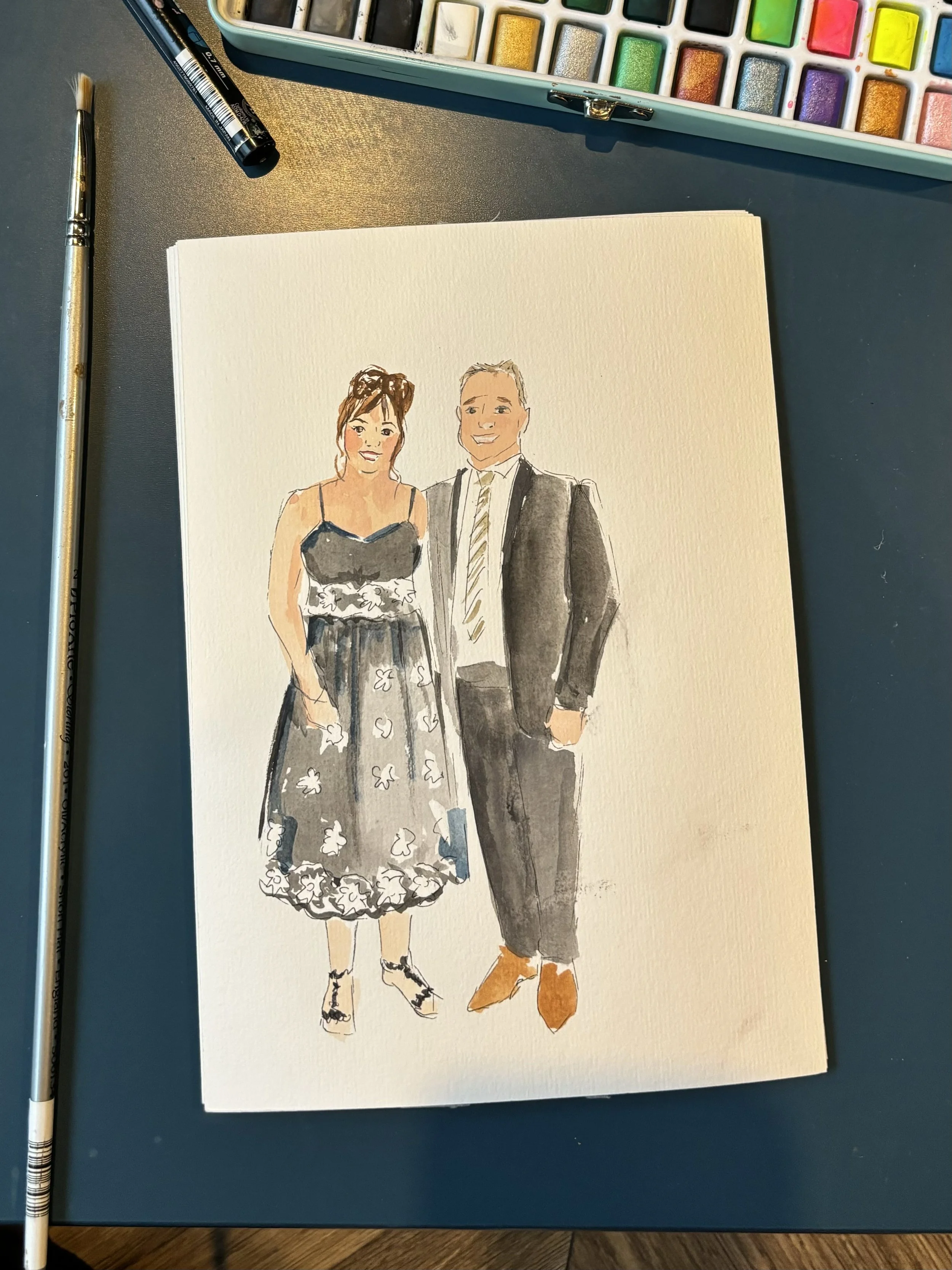 A watercolor sketch of a smiling couple dressed in formal attire, standing together. The woman is wearing a black and white floral dress with spaghetti straps and high heels, and has her hair styled in an updo. The man is wearing a suit with a stripe