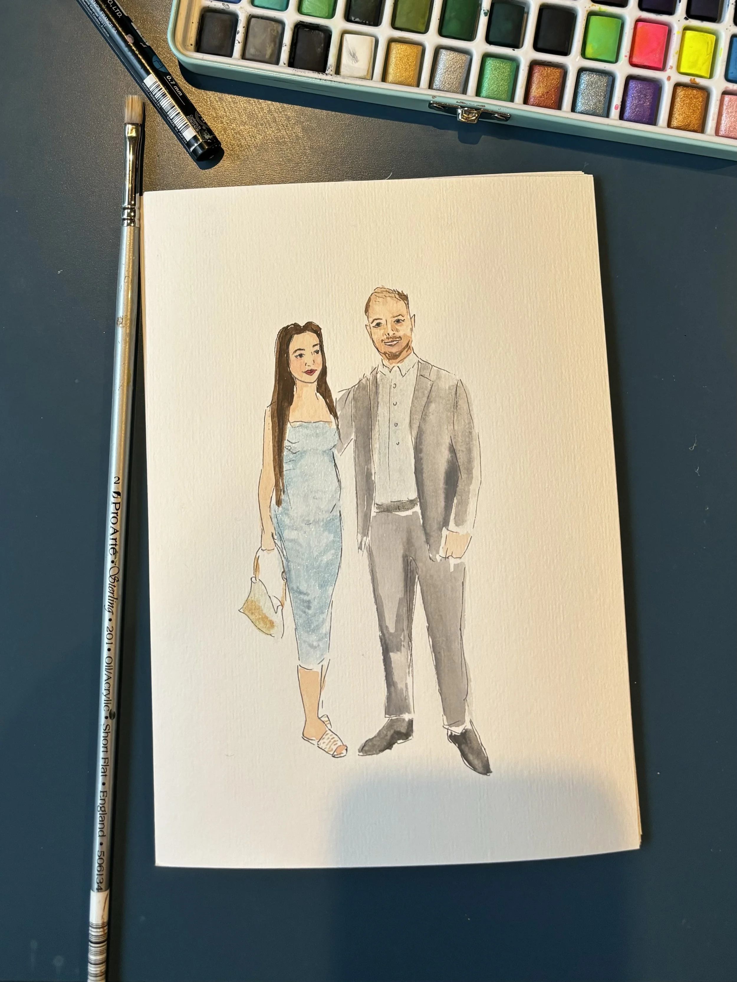 Watercolor illustration of a man and woman standing side by side, dressed in formal attire, with the woman holding a clutch. Art supplies, including a paintbrush and watercolor palette, are visible nearby.