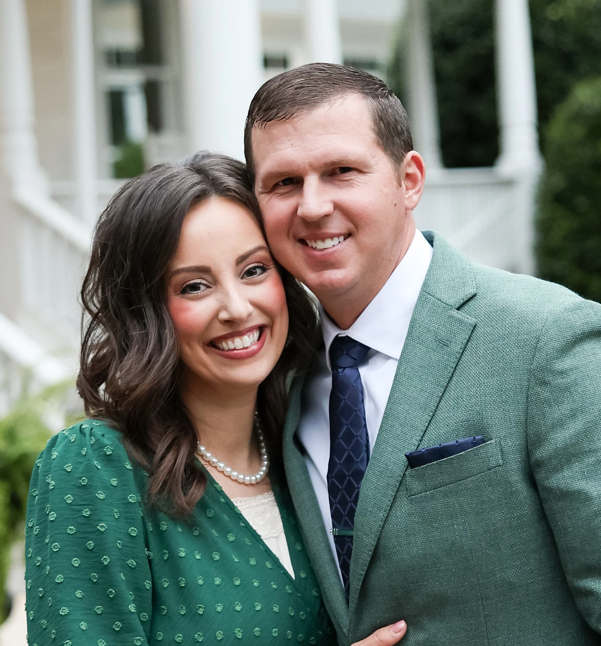 Randy and Victoria Kiker standing outside a white Southern home in Charlotte NC featuring fresh landscaping and lush green sod lawn
