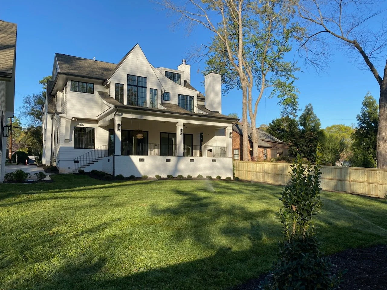 Fresh cut sod installation and landscaped lawn at a white modern home in Charlotte NC by Southern Pride Turf Farm.