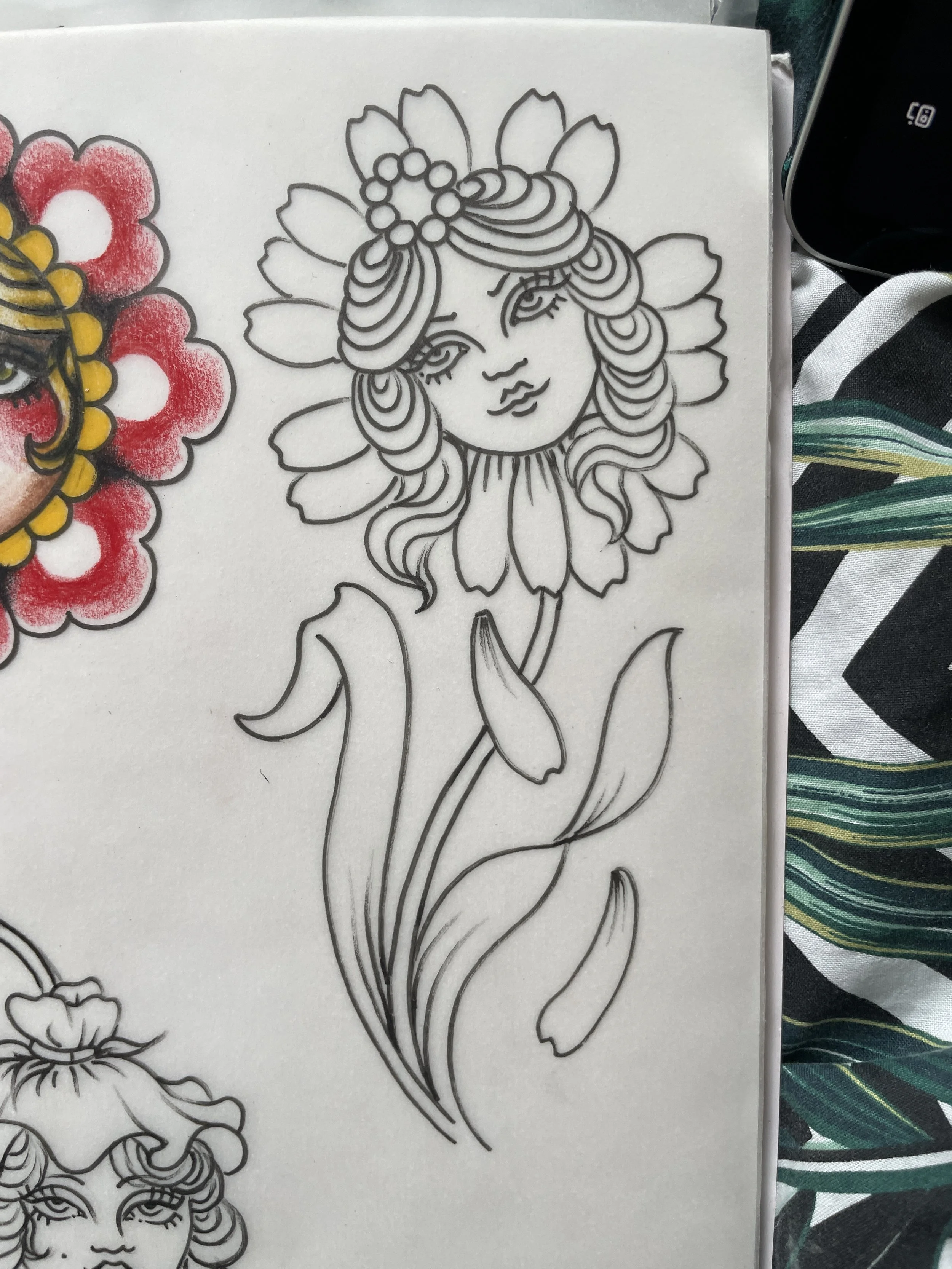 Outline drawing of a woman's face with closed eyes, wavy hair, and a flower crown, next to a partially colored floral design.