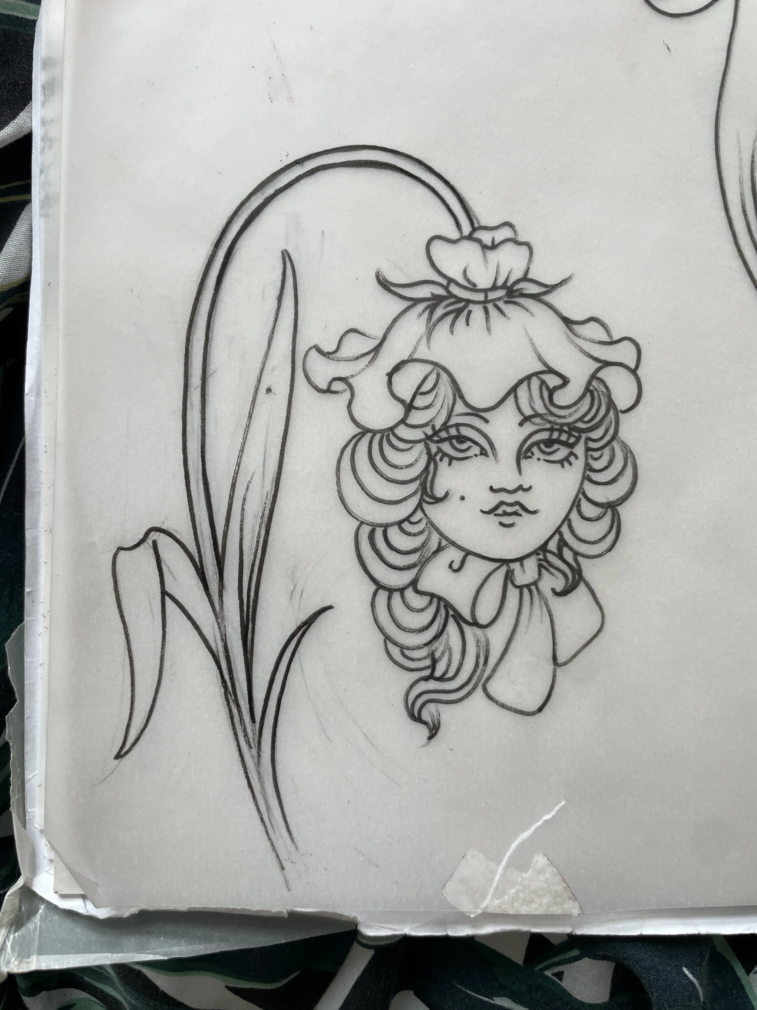 A black and white line drawing of a woman's face with curly hair, within a flower 