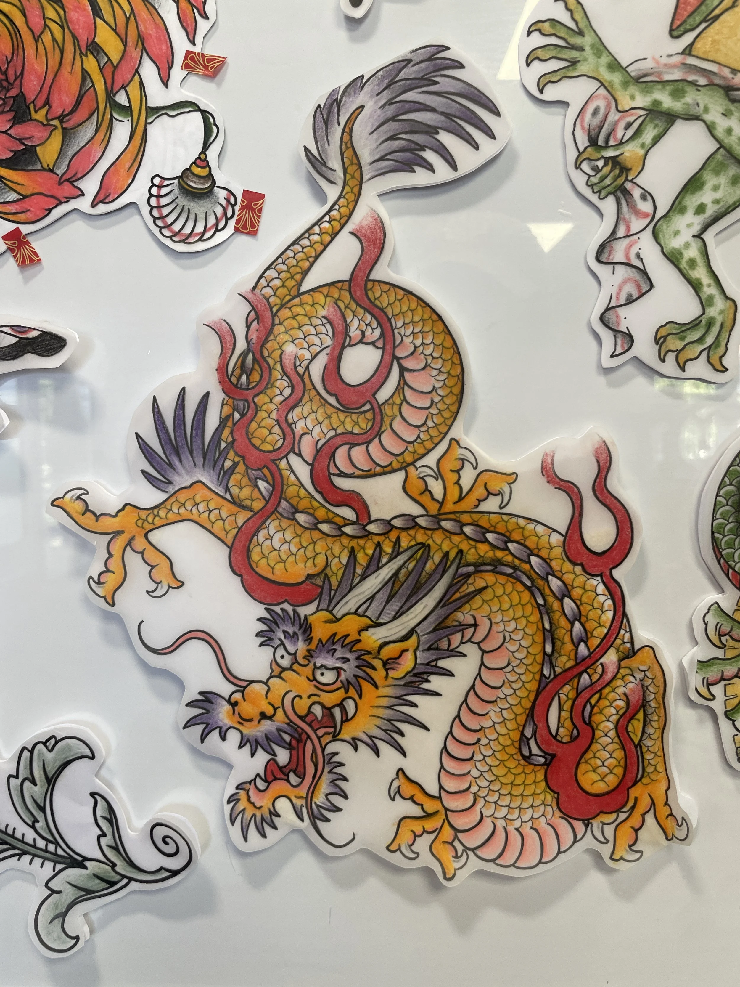 Colorful illustration of a traditional Chinese dragon with an elongated, scaled yellow-orange body, purple and red accents, and fierce facial features. The dragon is surrounded by stylized clouds and flames.