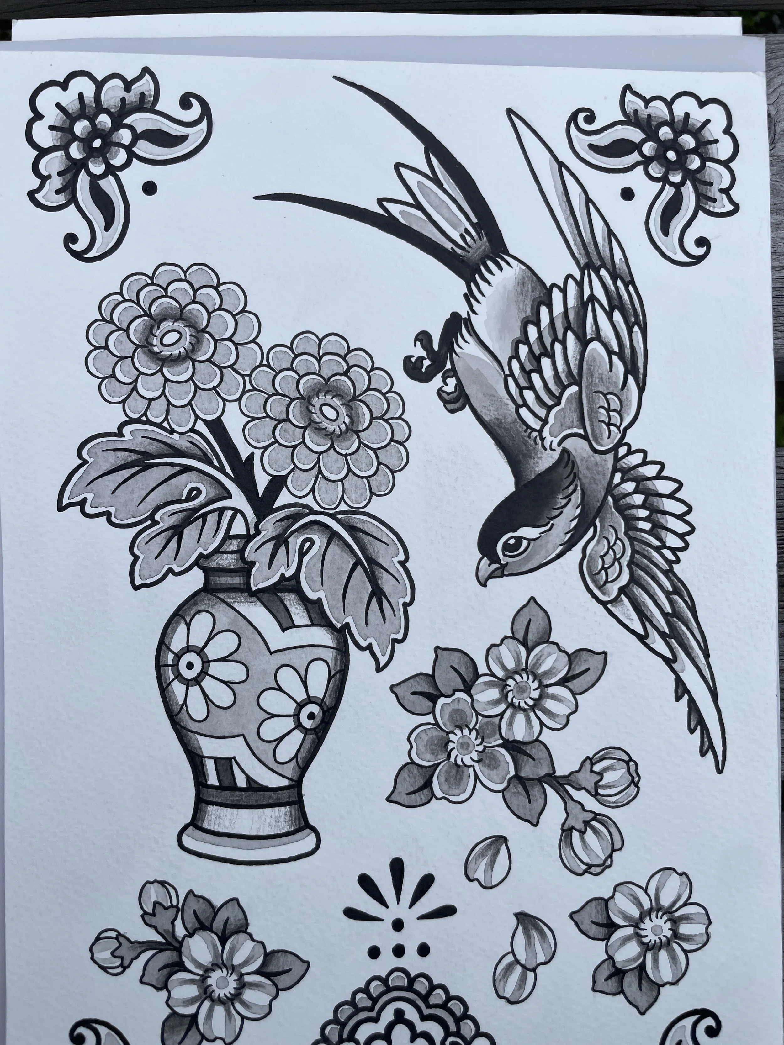 Black and white line drawing of a vase with flowers, a bird near the flowers, and additional floral and ornamental designs.