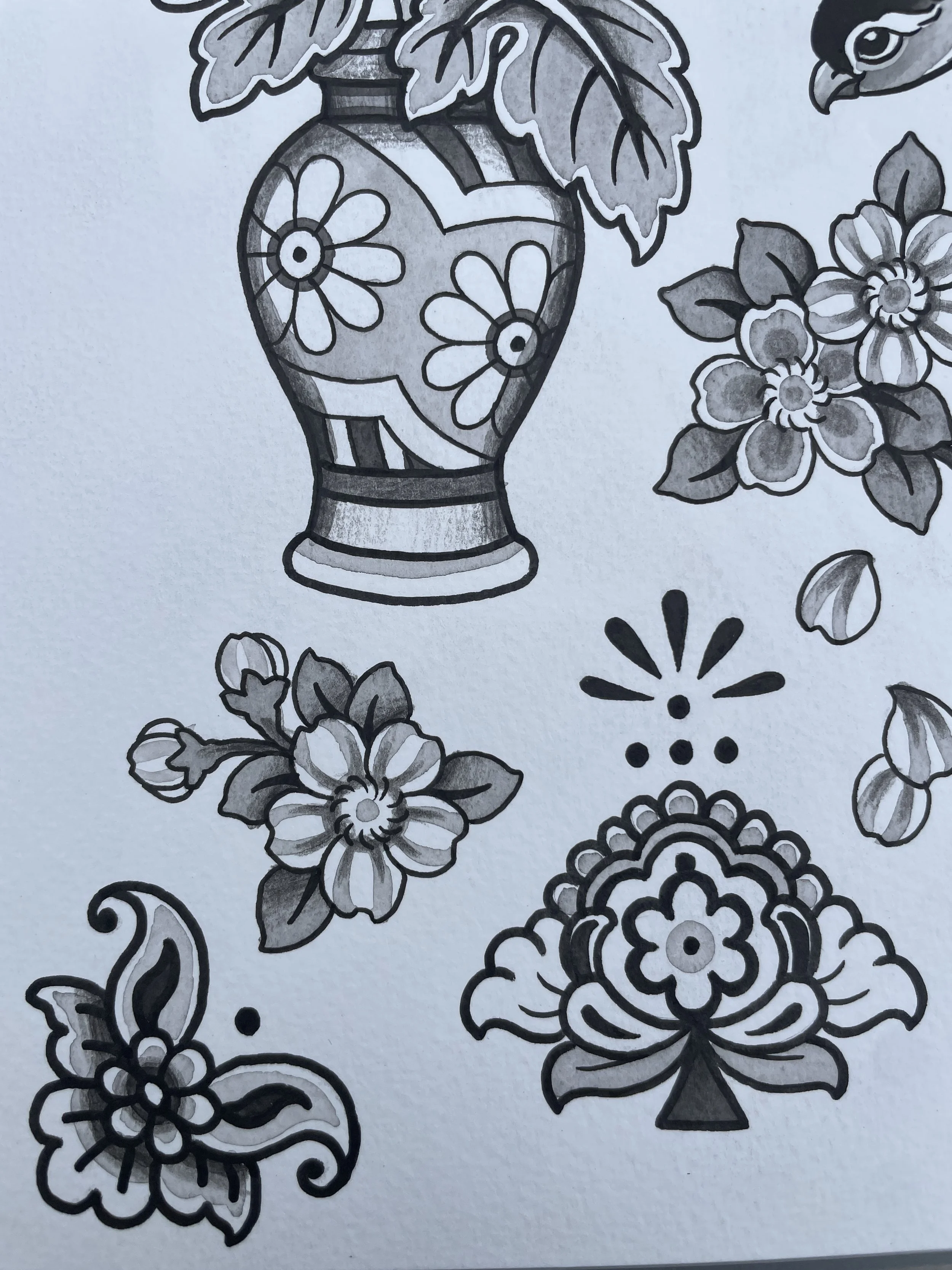 Black and white drawing of a floral design with a vase, flowers, and leaves.