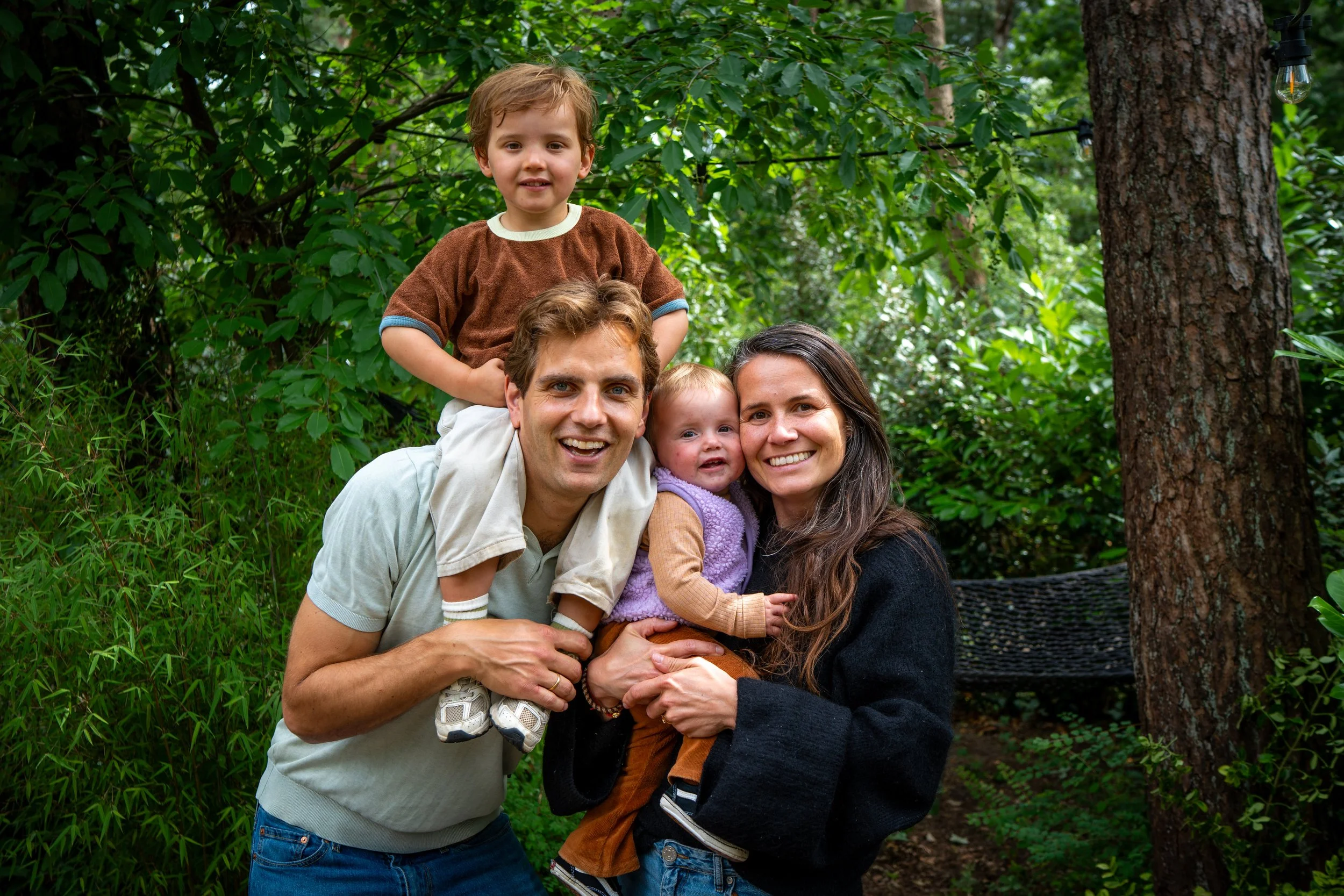 Gezin in een bos, zittend op een bankje, lachend en knuffelend