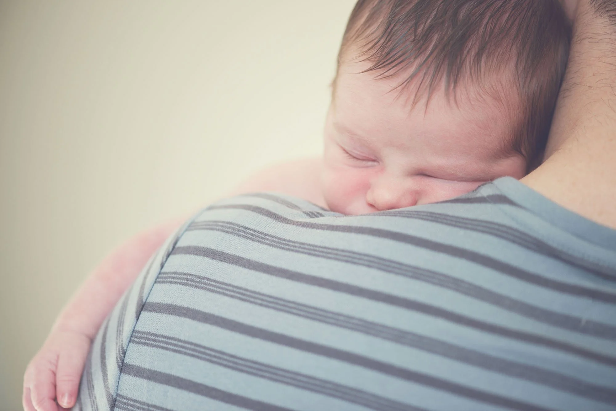 A newborn baby is comforted on his father's shoulder and snuggles in against his father's neck, during a newborn photoshoot in Kentish Town in North London.