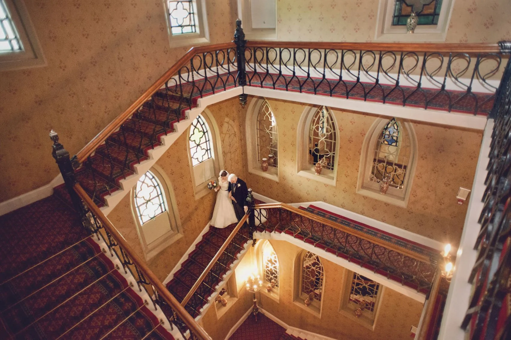 A bride walks down the staircase with her father ahead of her wedding ceremony at The Randolph Hotel in Oxford 