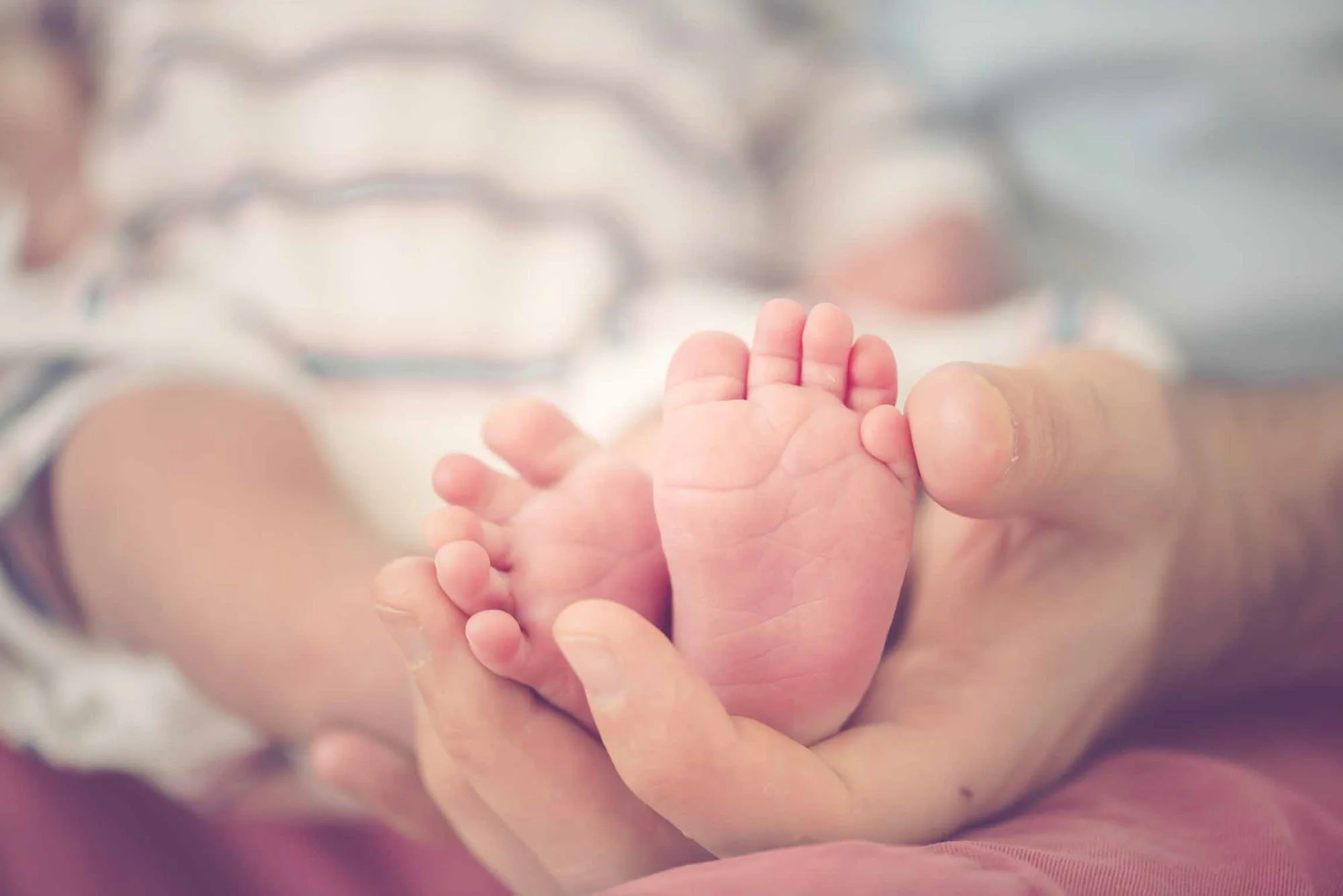 A new father holds his newborn baby's feet in his hand, during a newborn photoshoot in Finsbury Park in north London.
