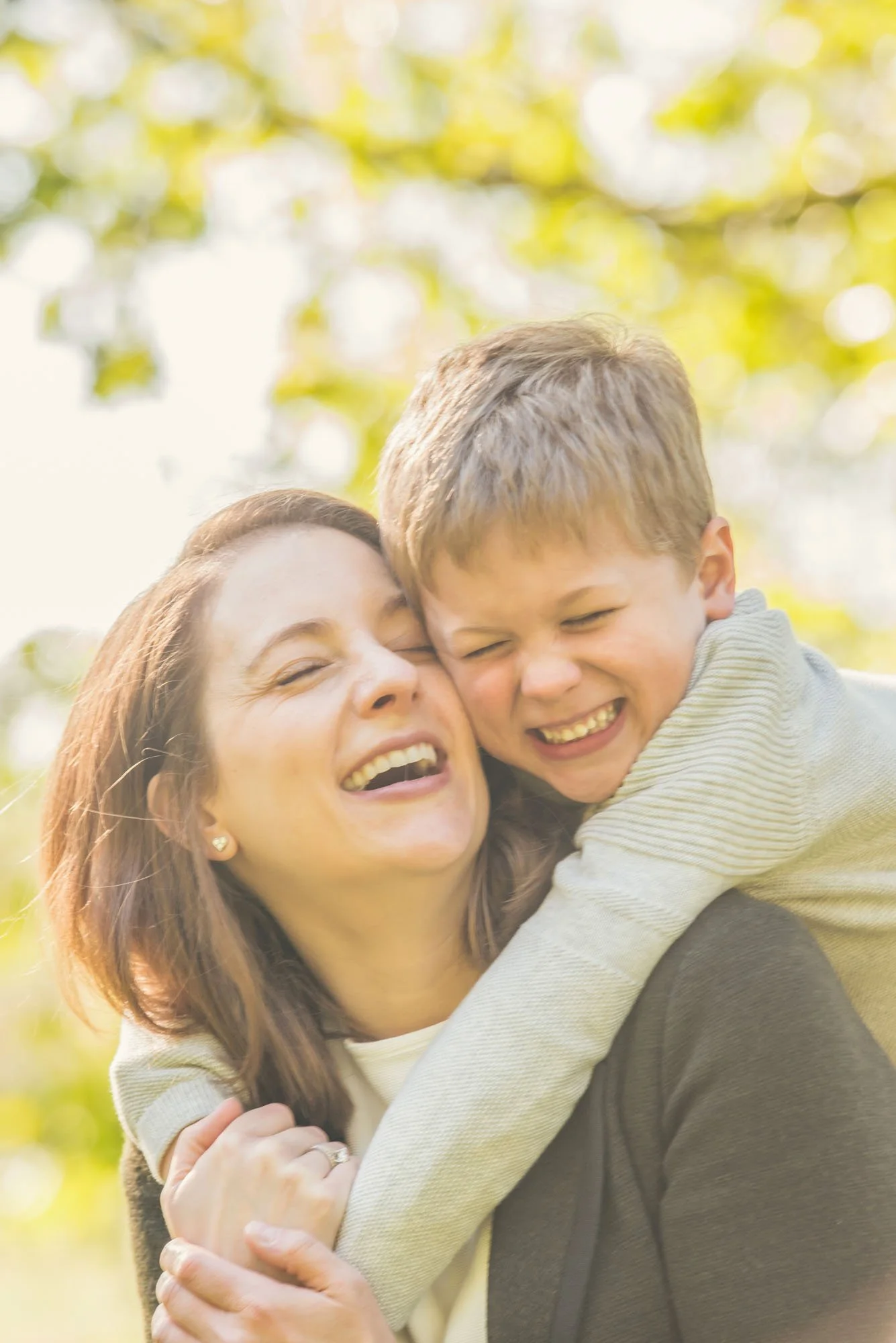 A little boy hugs his mother tightly and both smile delightedly during a family photoshoot in Hampstead Heath in north London 