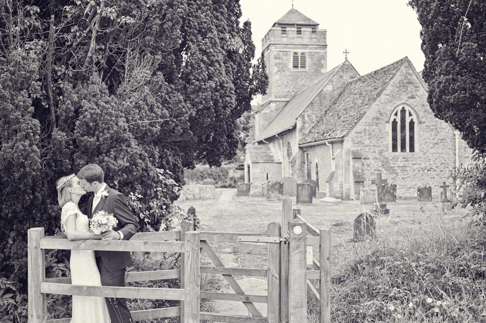 A bride and groom share a passionate kiss in a kissing gate in front of the Oxfordshire church where they were married