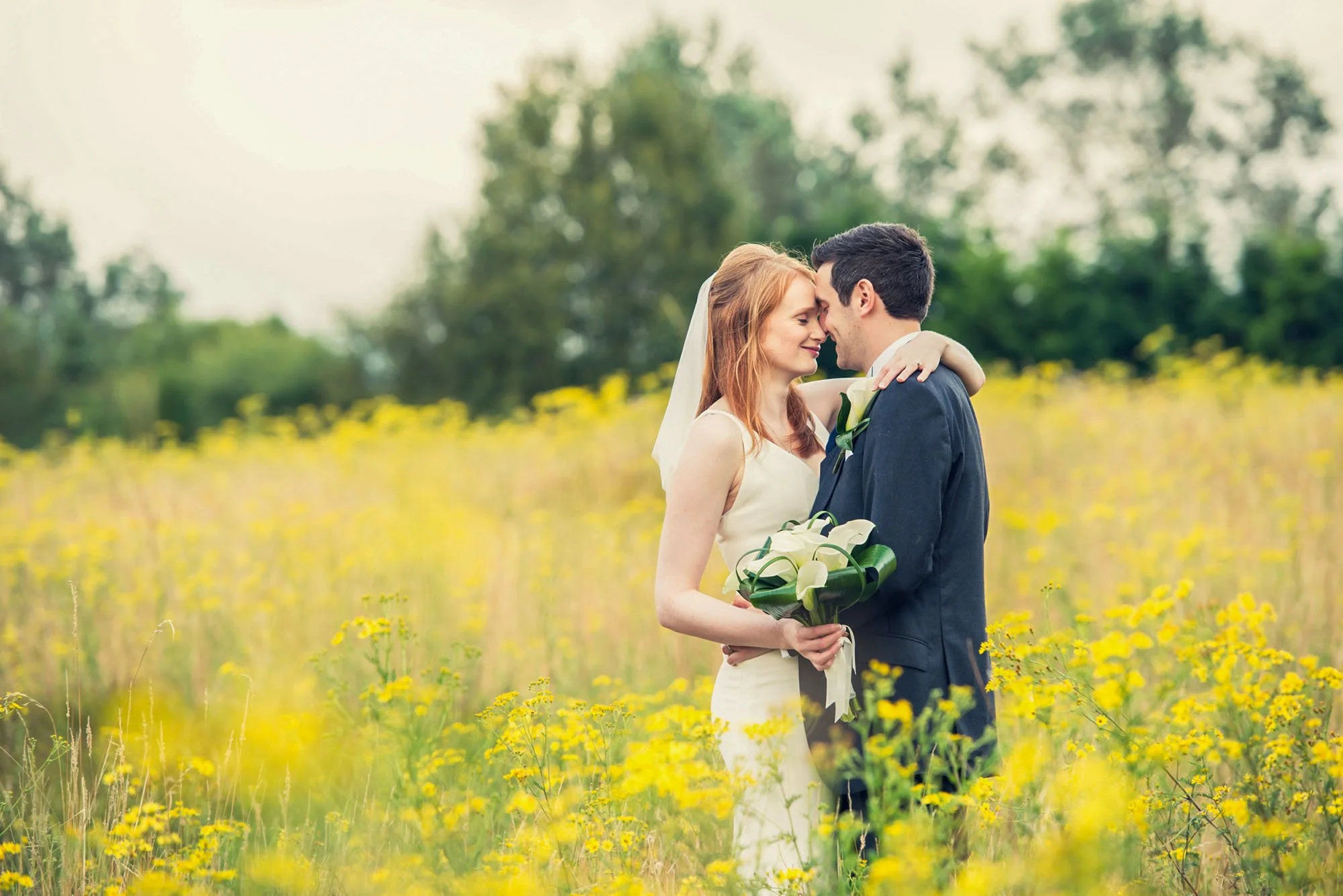 Bride and groom share a quiet love-filled moment in a field of yellow flowers at Essendon Country Club in Hertfordshire
