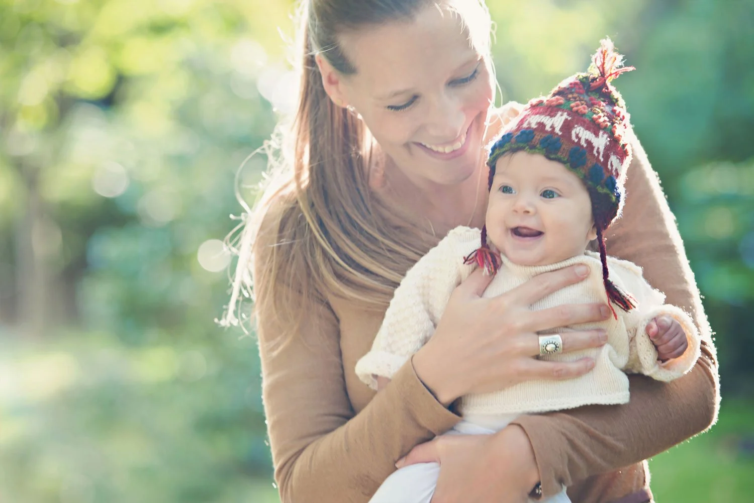 Proud mother hugs and smiles at her baby during a family photoshoot in Holland Park in London