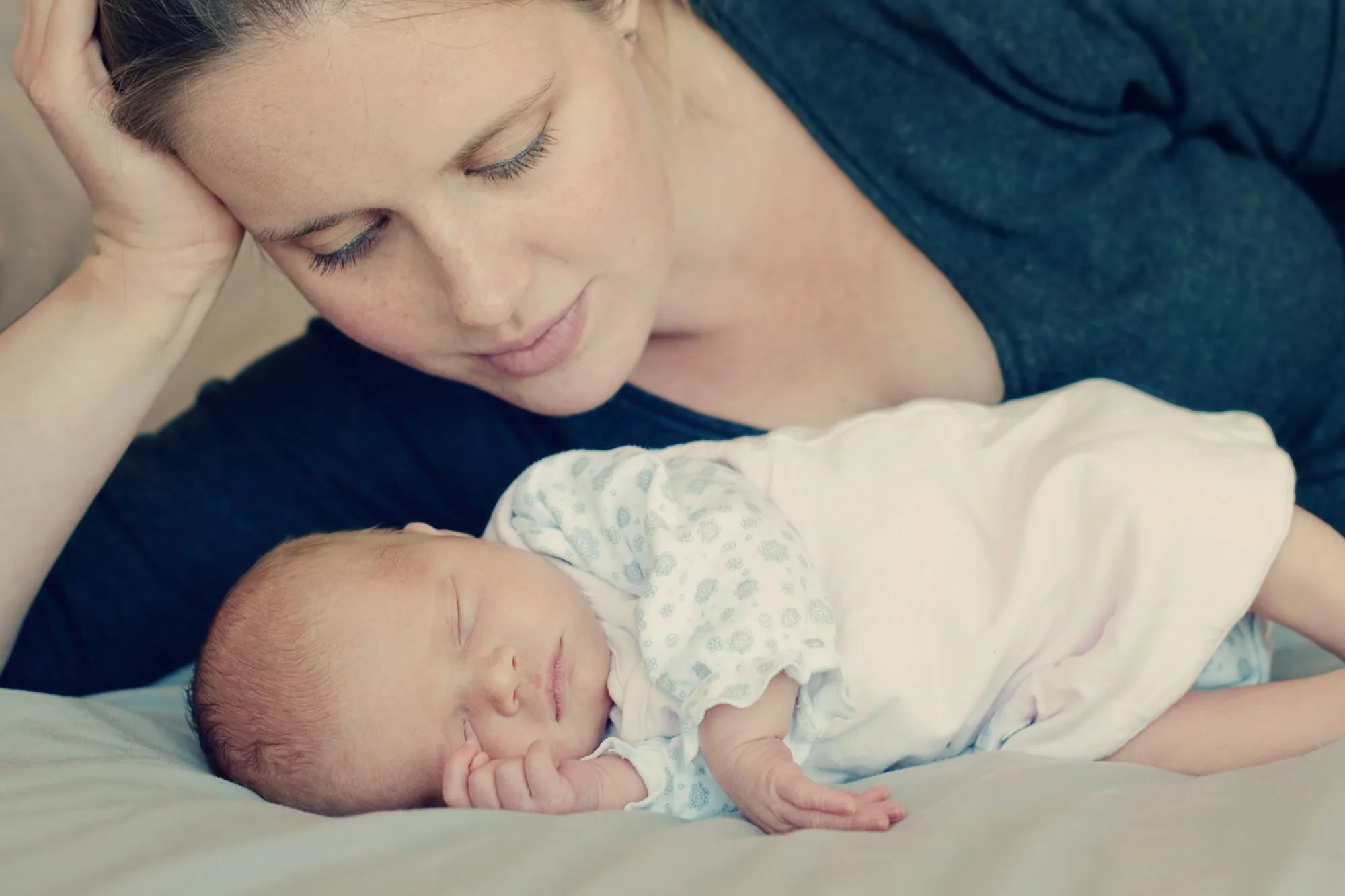 A new mother lies on her side and gazes down at her newborn baby at their home in Islington in north London