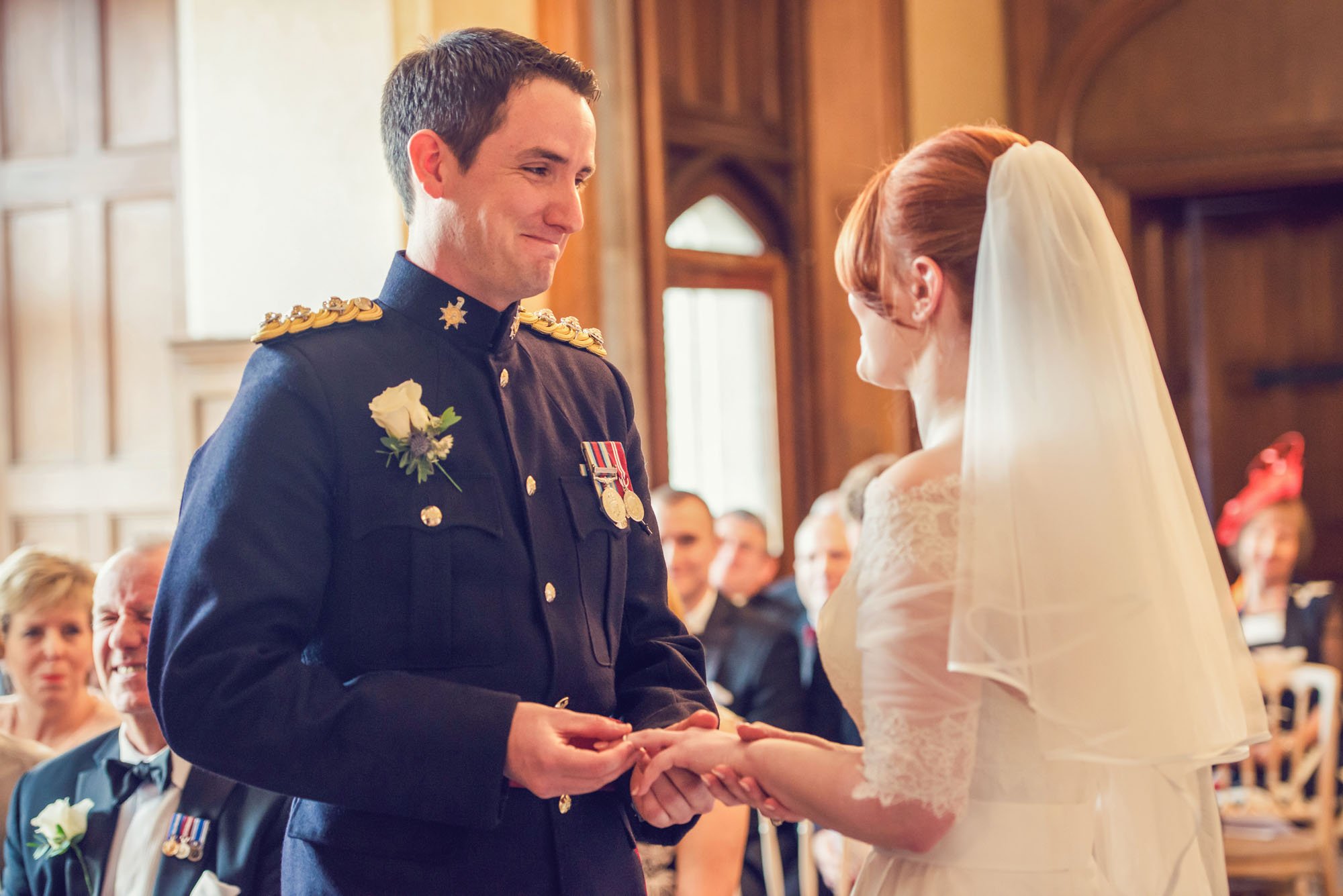 During a wedding ceremony at Froyle Park in Hampshire, a groom looks at his bride emotionally as he places a wedding ring on her finger