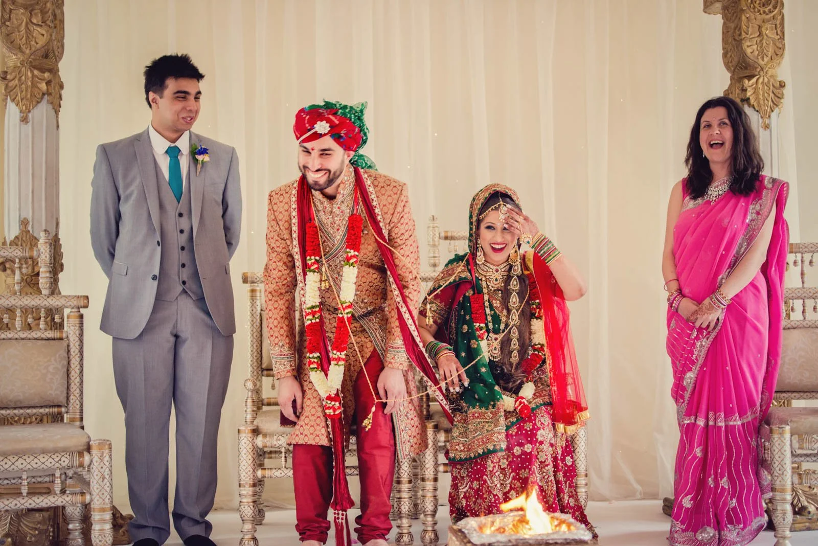 An asian bride and groom laugh during their asian wedding ceremony in west London