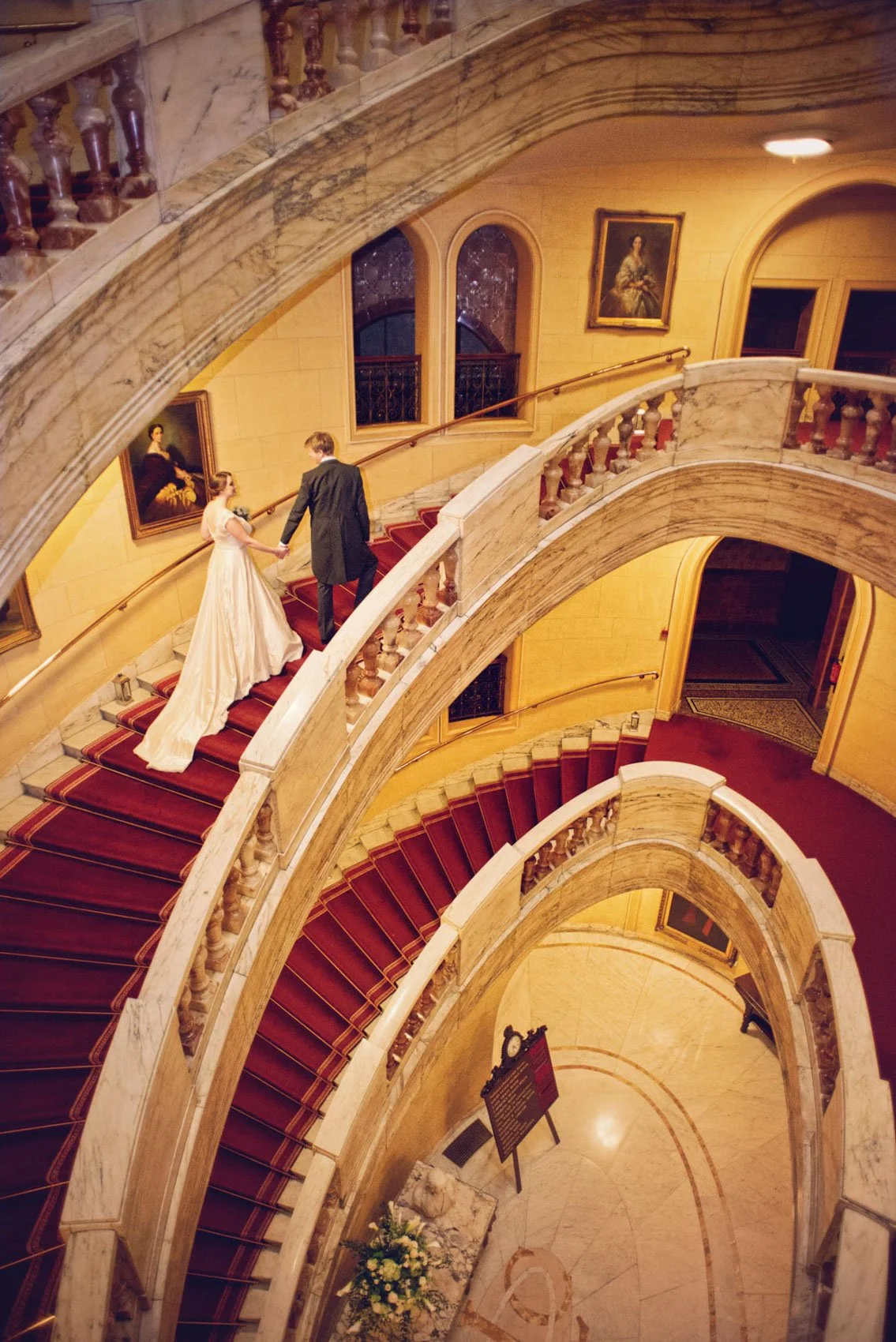 A groom leads his bride up the stairs during their wedding reception at One Whitehall Place in London