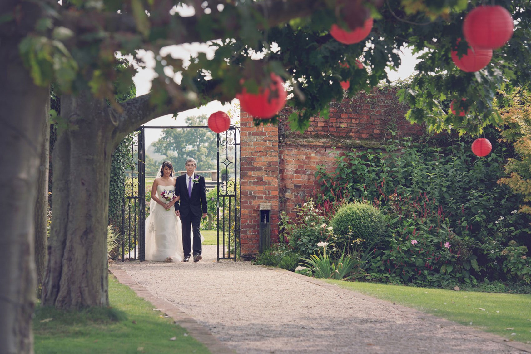 A bride's father walks her through the gardens at Gaynes Park near Epping in Essex, ahead of her weekday wedding ceremony at Gaynes Park