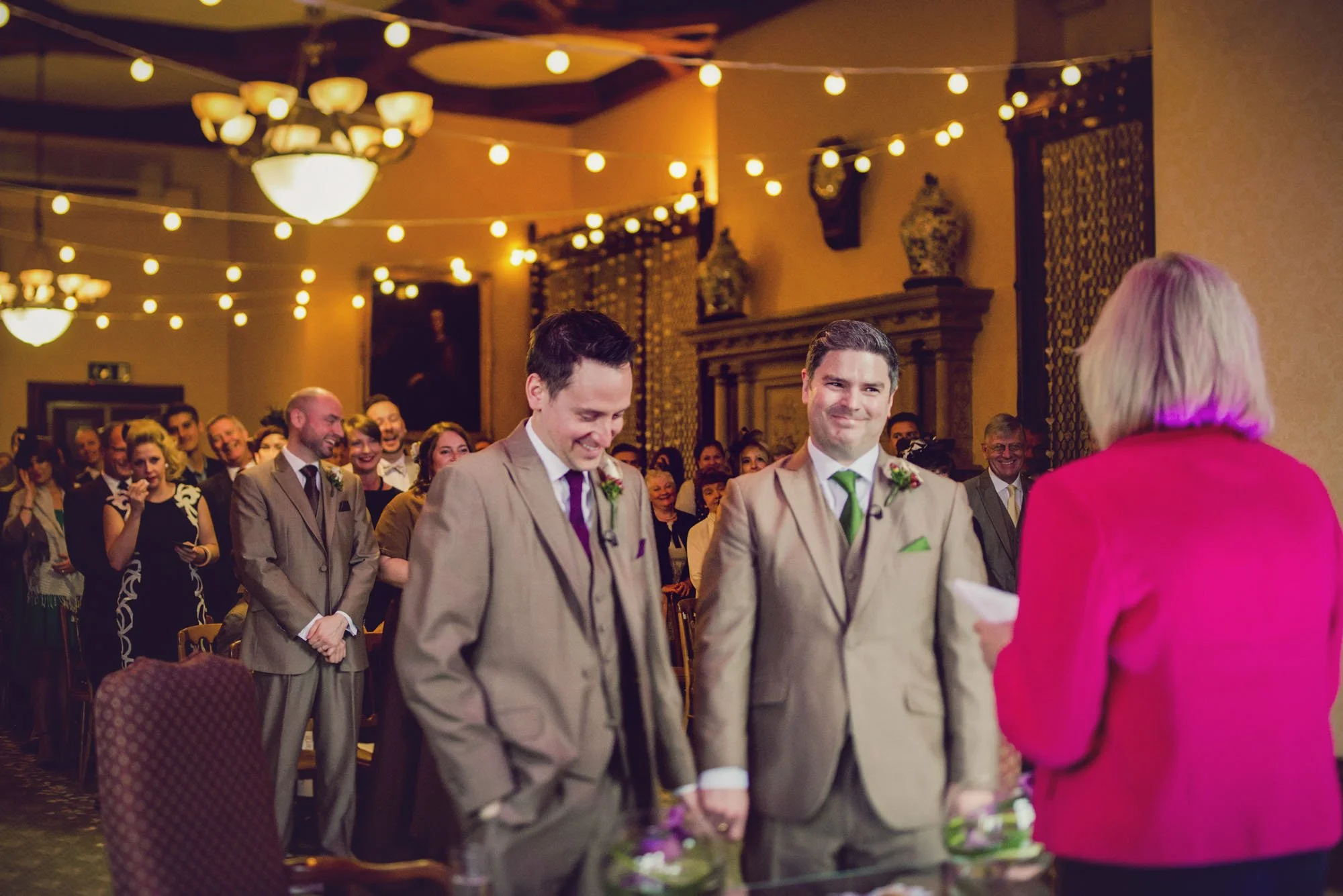 Two grooms hold hands and look emotional during their wedding ceremony at Elvetham Hotel in Hampshire