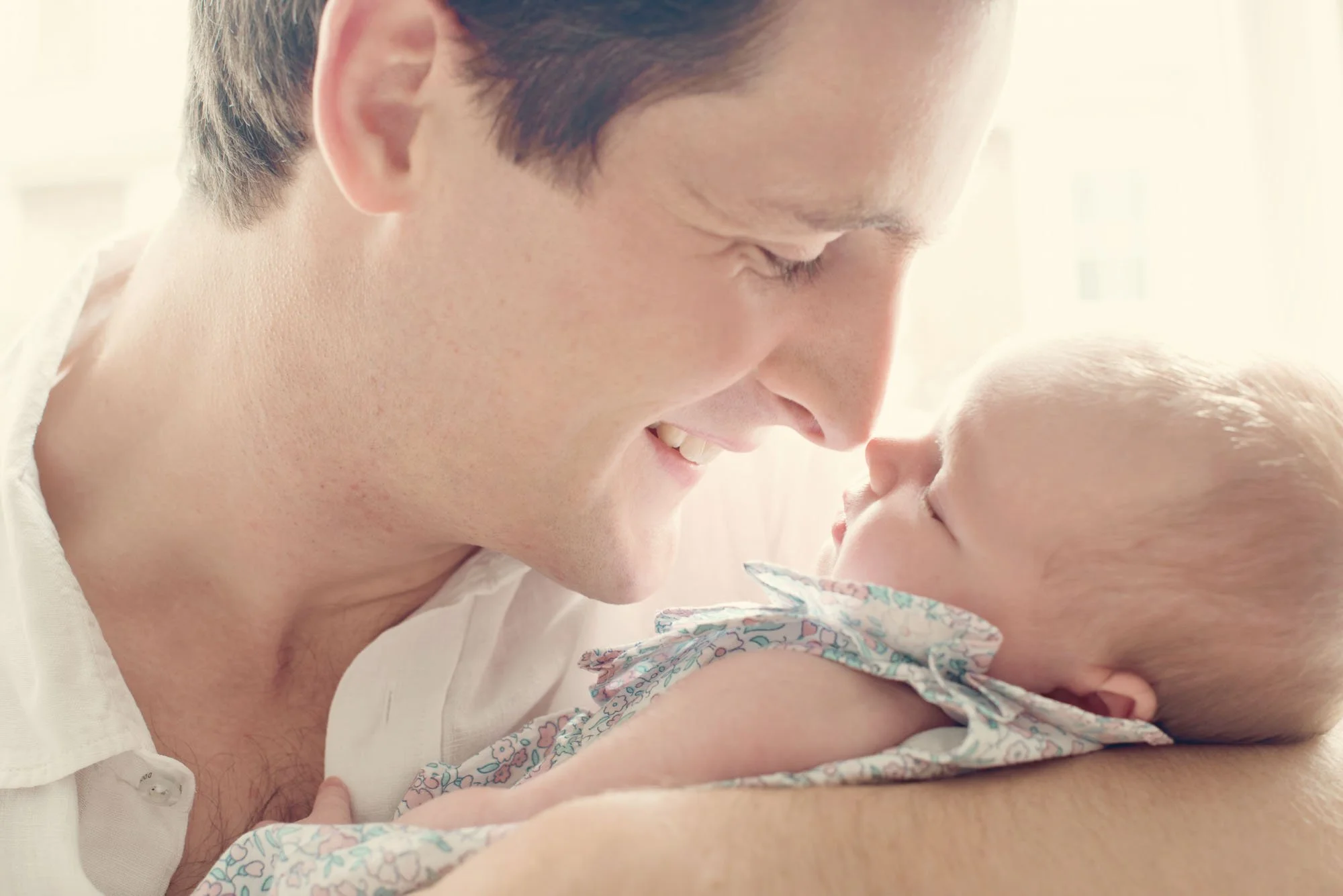 A proud new father rubs noses with his newborn baby during a newborn photoshoot in Islington in London