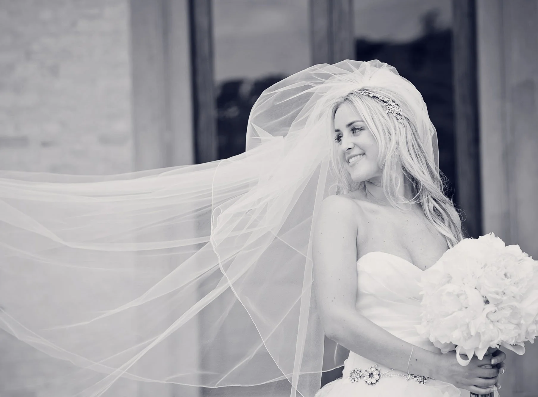 A black and white photo of a bride holding her bouquet with her veil floating behind her, during her micro wedding in Marylebone in London 