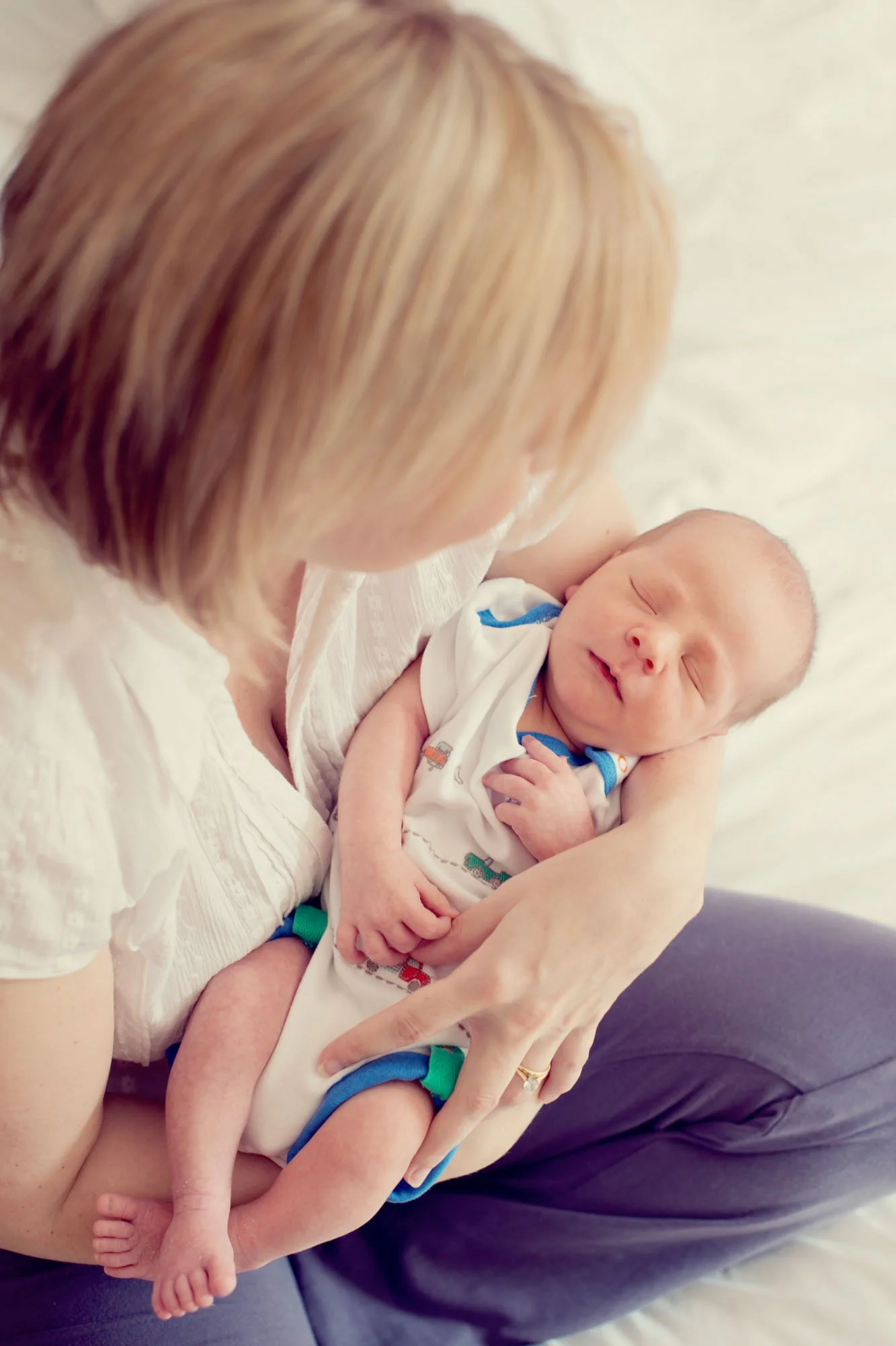 A new mother holds new newborn baby boy in her arms and looks down at him at their home in Putney in south west London