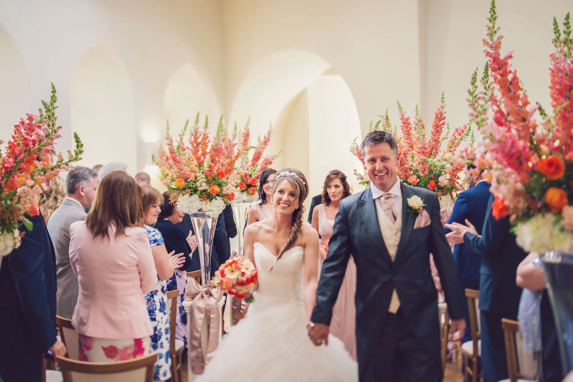 Bride and groom smiling as they exit their wedding ceremony at Farnham Castle in Surrey