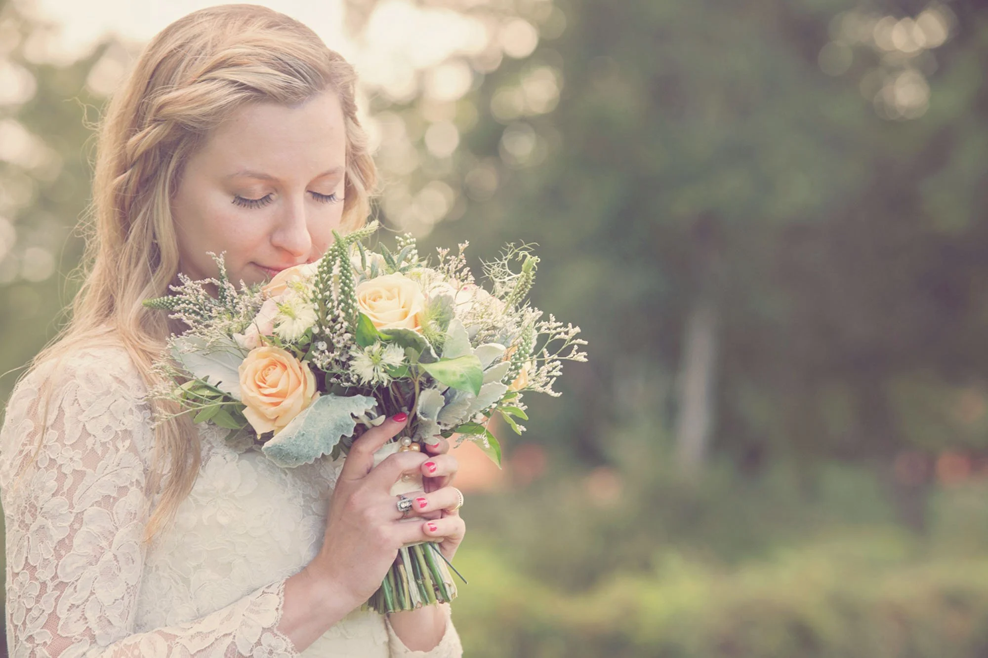 Bride smells her bouquet in the late afternoon sun at Regent's Park London