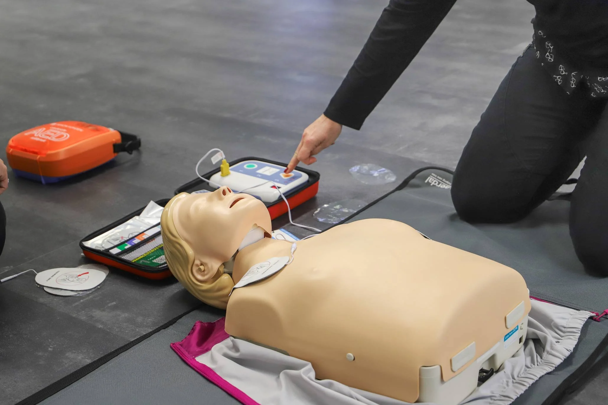 A Basic Life Support training instructor demonstrates how to use a defibrillator on a dummy during a CPR training.
