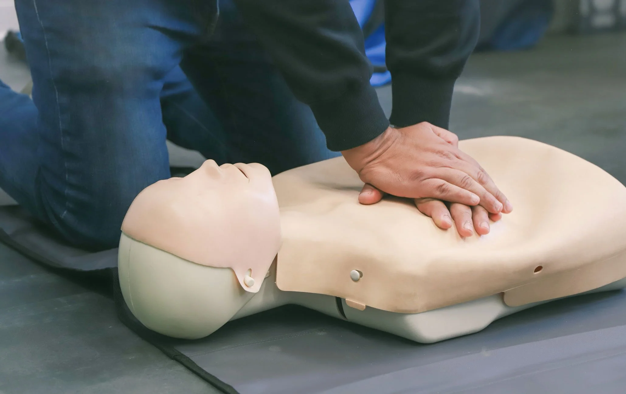 BLS training professional demonstrates CPR on a dummy.