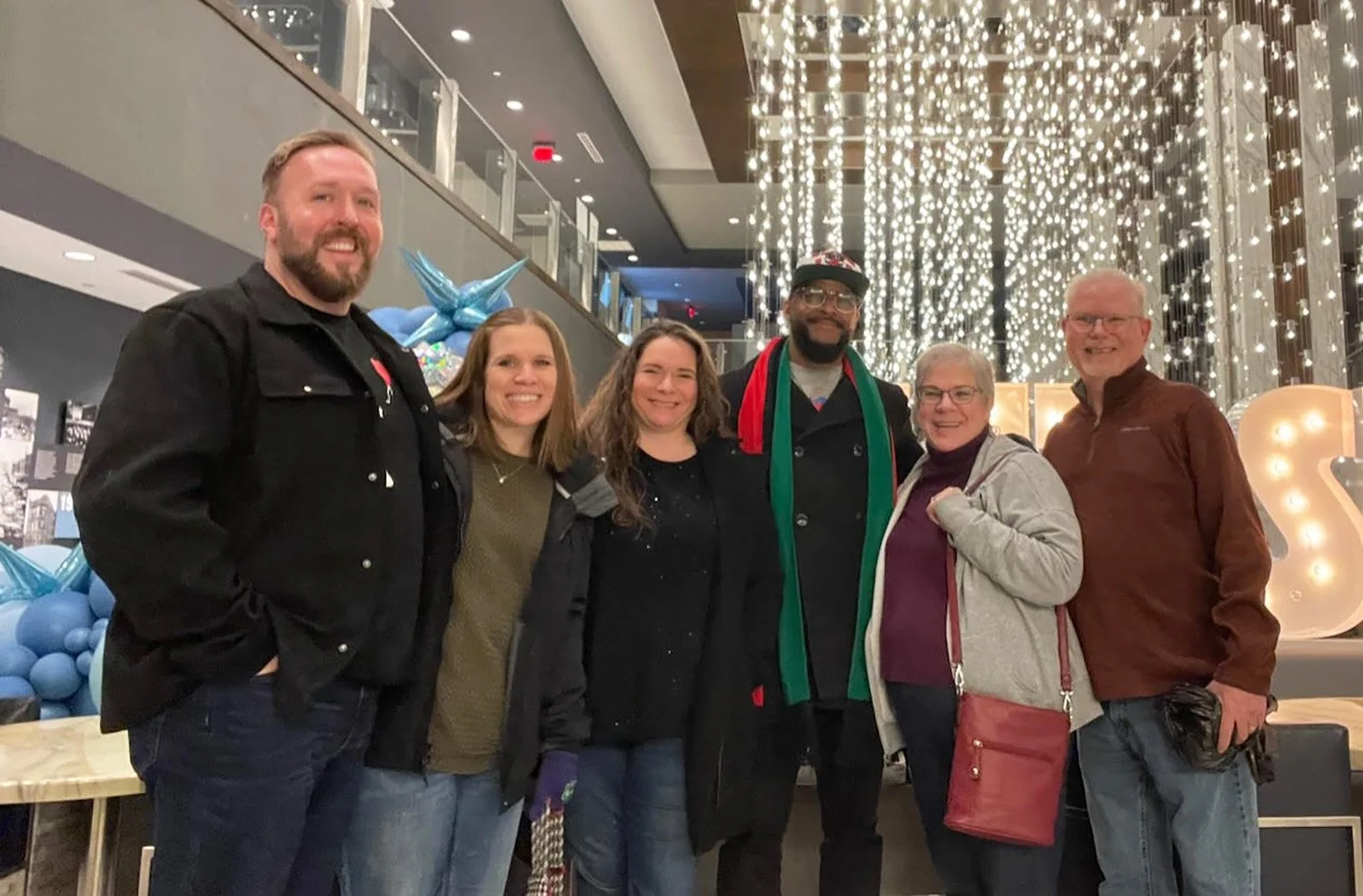 Kenny and Susan Smith posing with family members inside a hotel lobby decorated with hanging lights.
