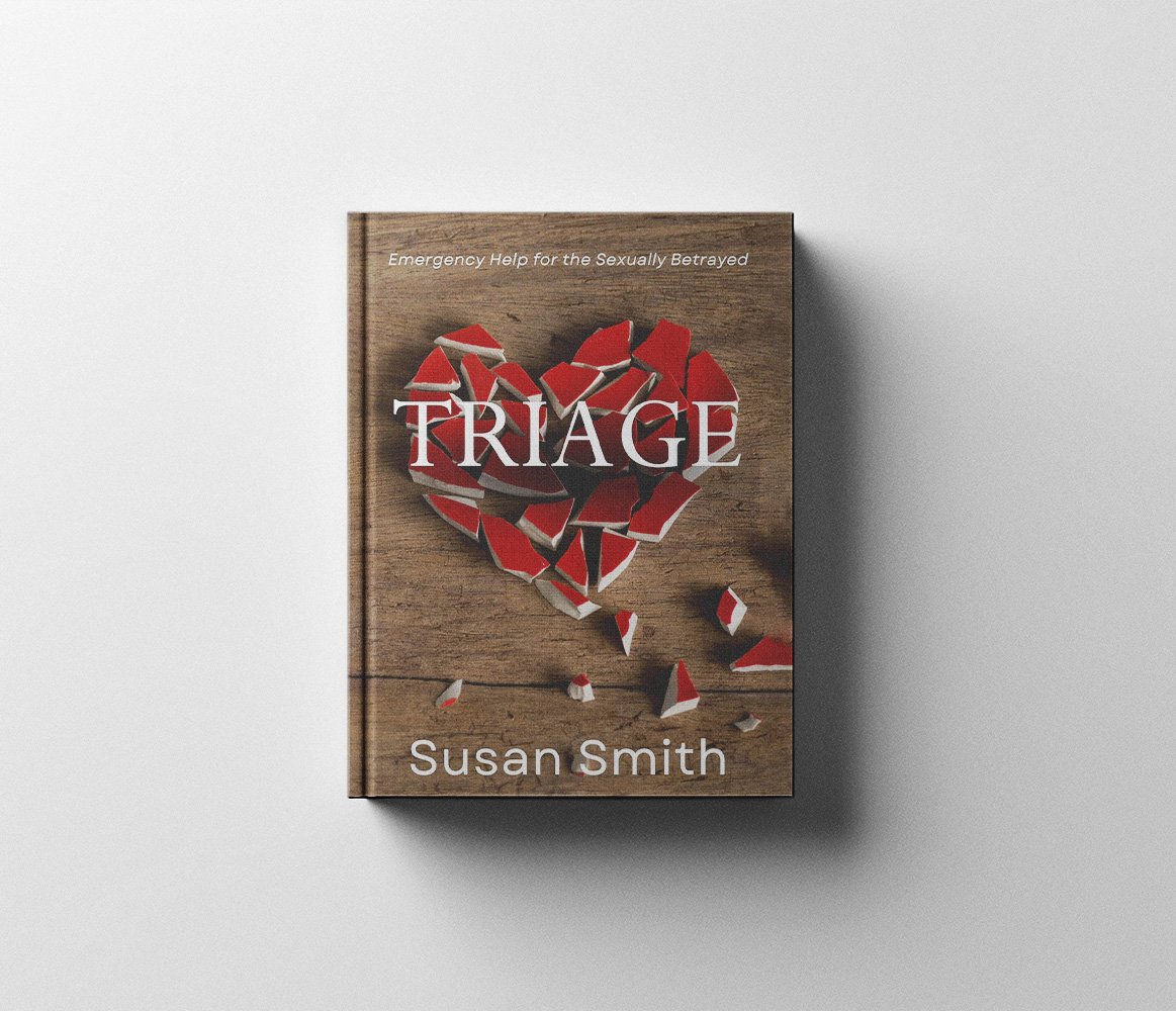 A book titled 'Triage' by Susan Smith with a cover design featuring a broken heart made of red and white ceramic pieces on a wooden surface, with a shadow cast on the right side.