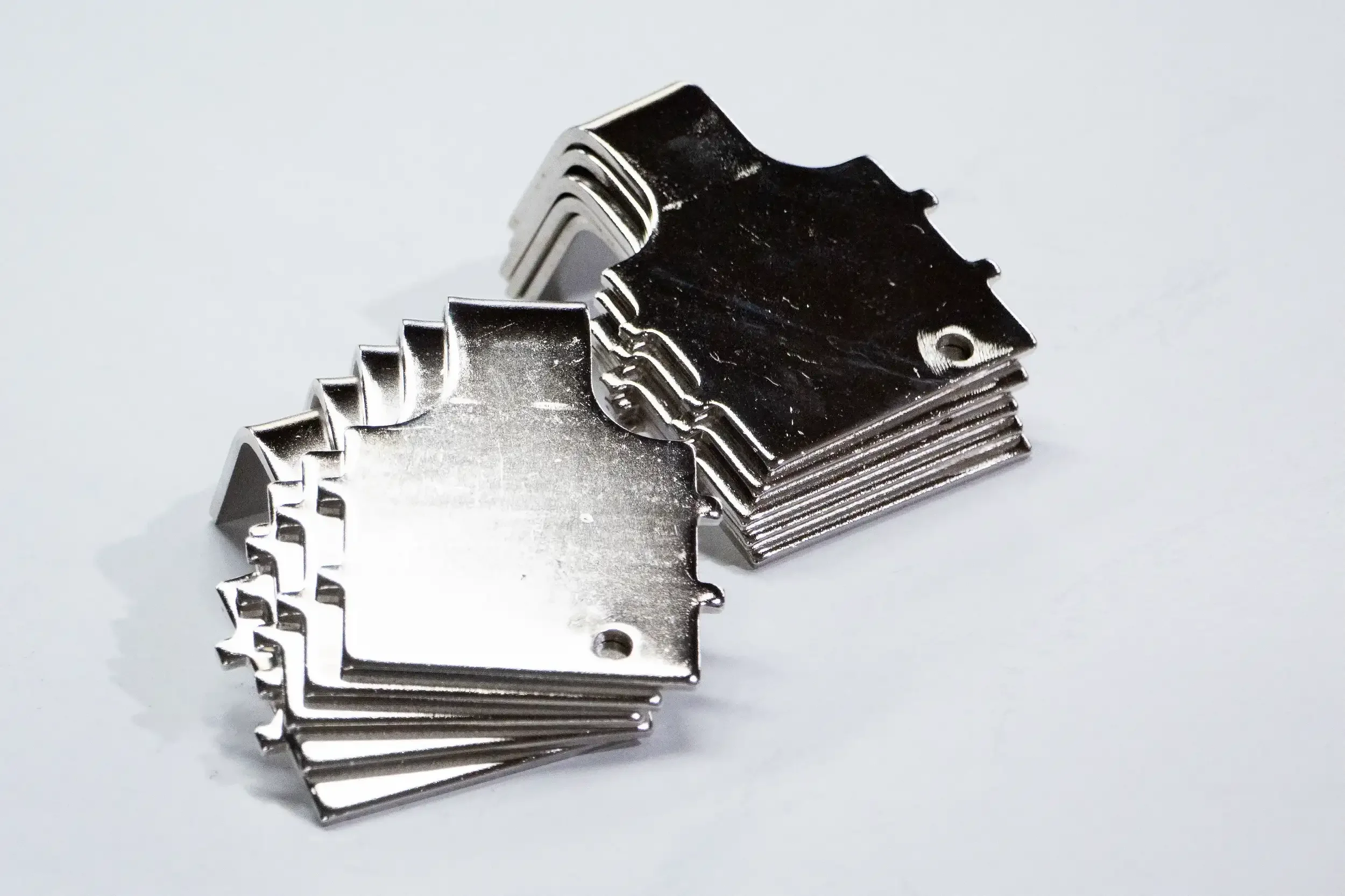 Stacked metalshapes with jagged edges, on a white surface.
