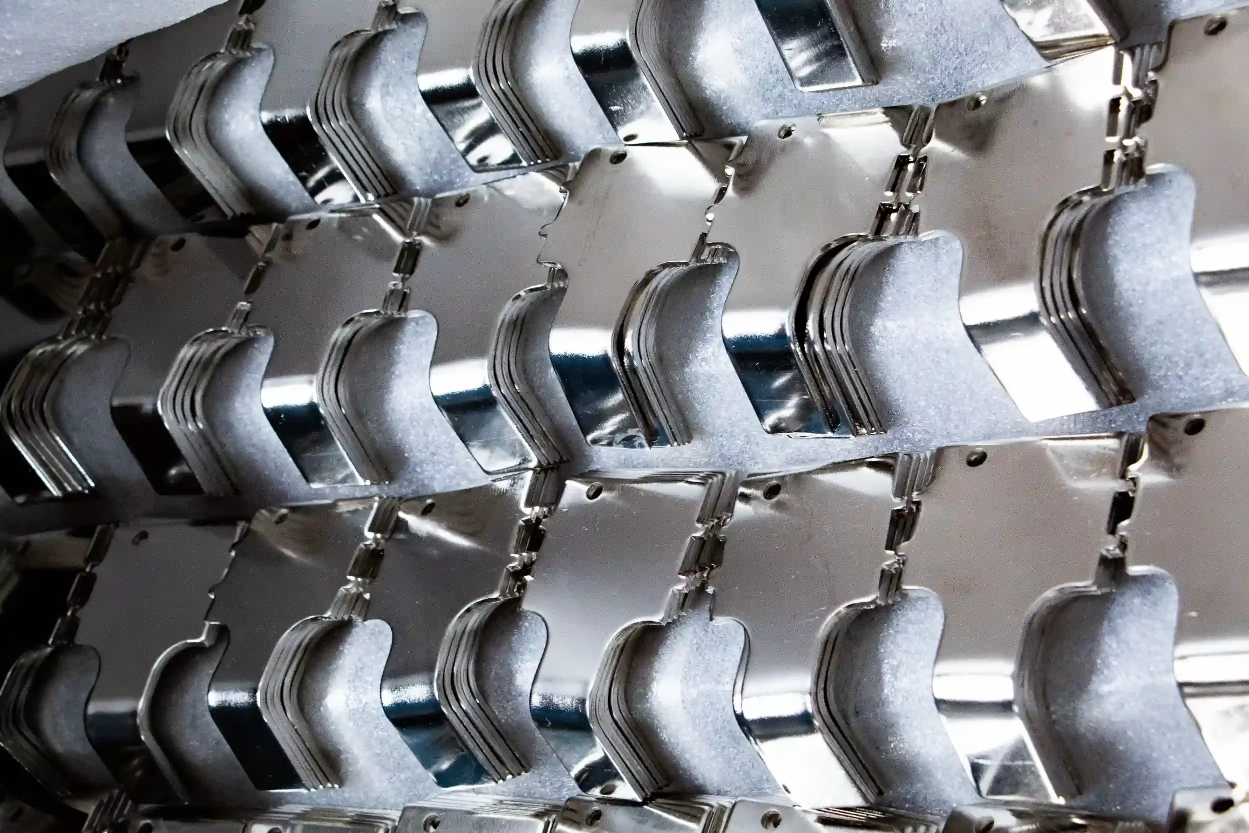 Multiple metal electronic components or parts arranged in rows in an industrial or manufacturing setting.