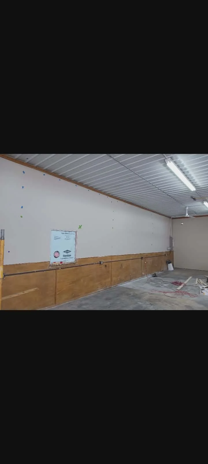 Interior of a room under renovation with a wooden lower wall, exposed wiring, and construction tools on the floor. Bessemer Small Engine remodel. After paint project picture