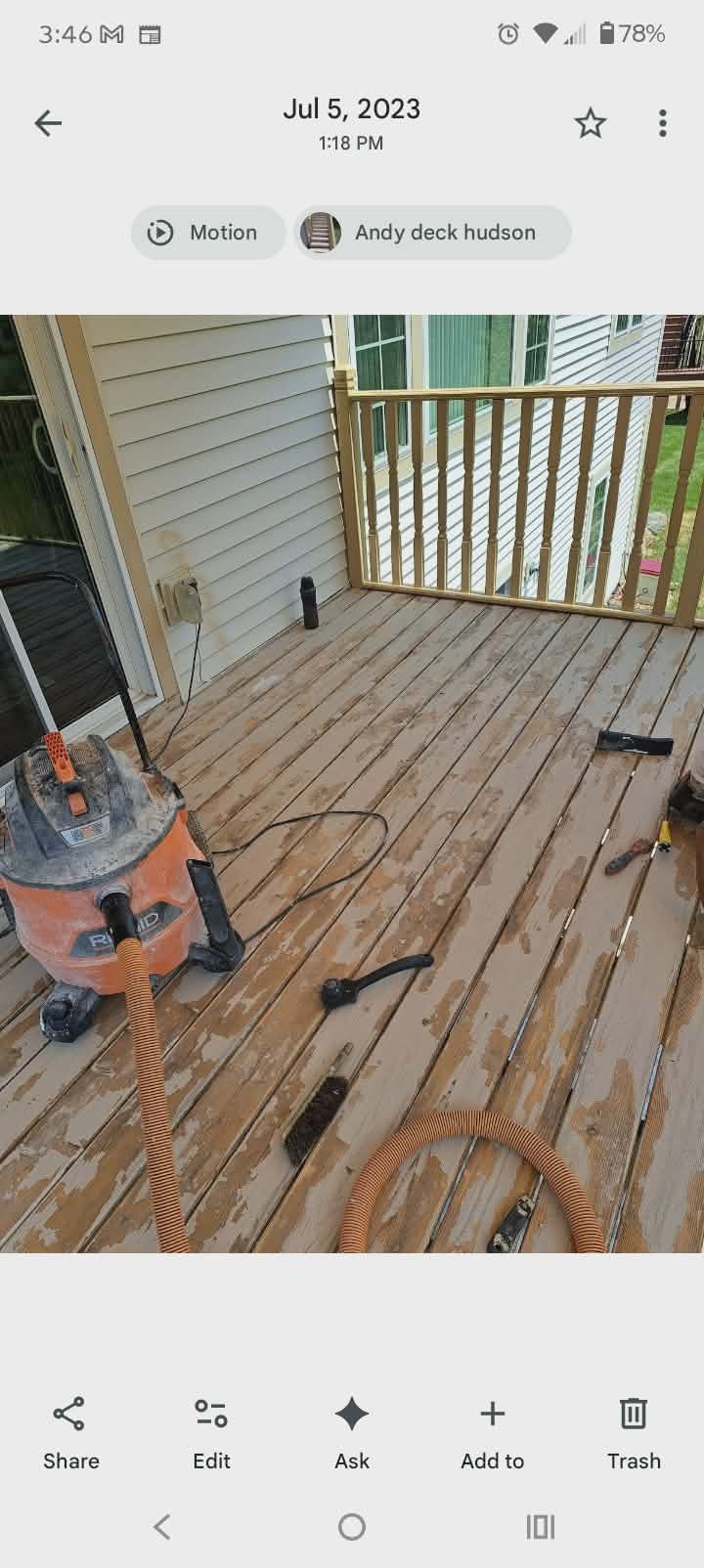 A wooden deck renovation in progress, with tools and cleaning equipment, including a vacuum, on the deck, attached to a house with siding and a railing.