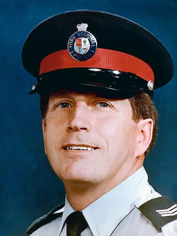Portrait of a police officer wearing a uniform and a cap with a 'York Regional Police' badge, against a plain background.