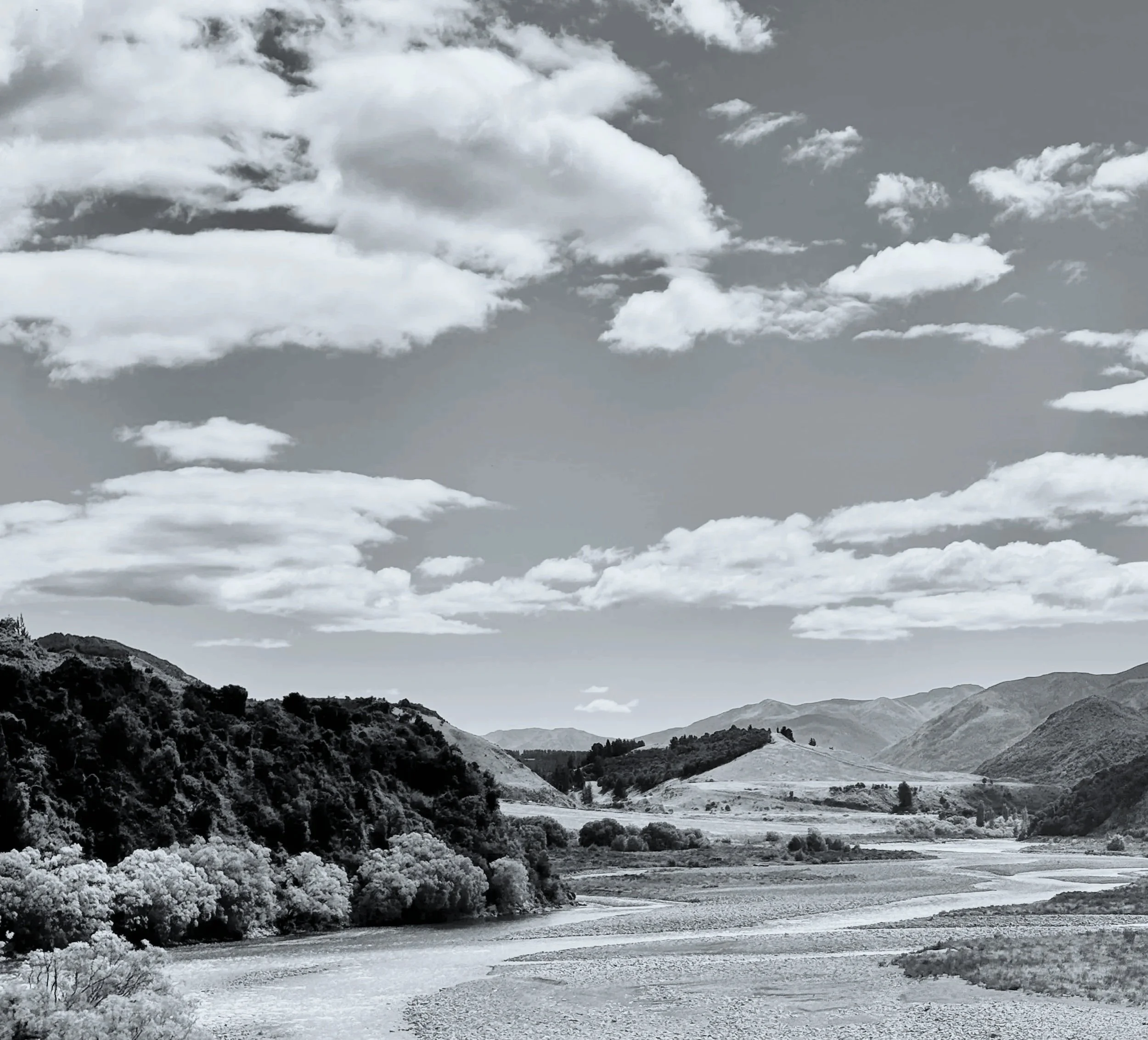 Scenic view of mountainous landscape with hills and a river, black and white photo.