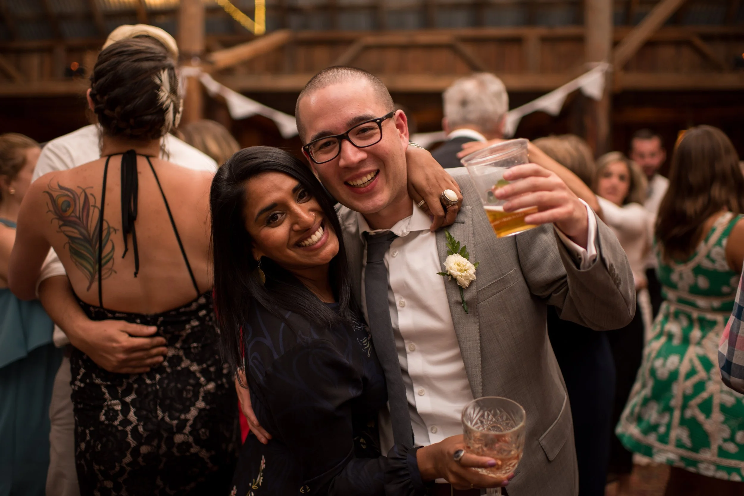 People celebrating at a social event with one person holding a drink and both smiling.
