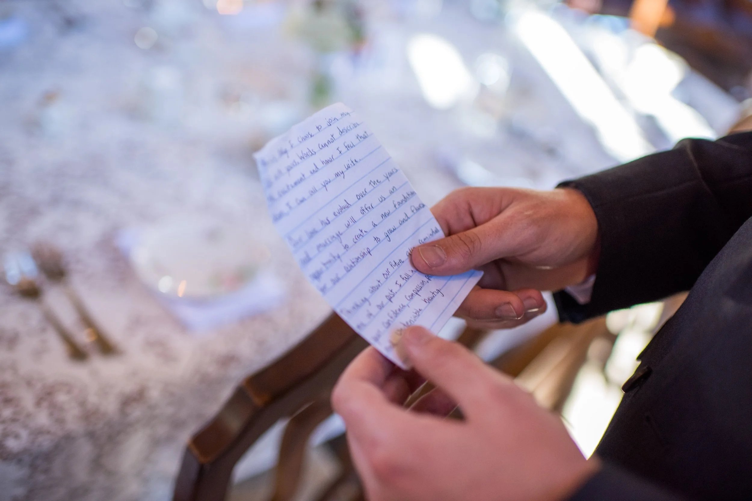 Person holding a handwritten letter or note, with a blurry background.
