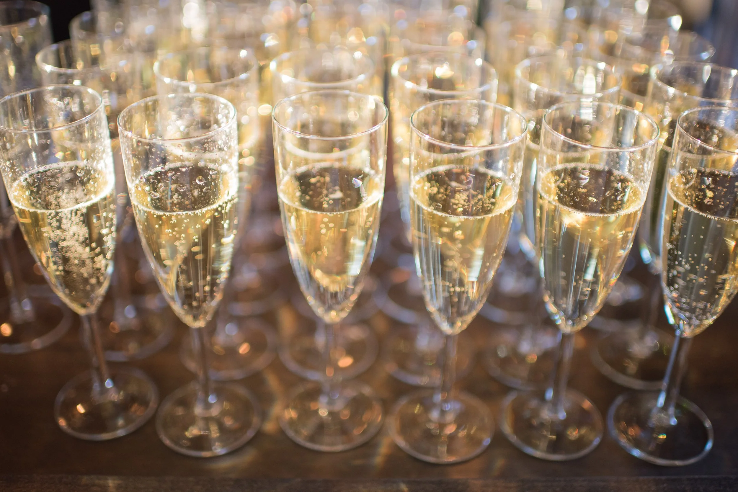 Several champagne glasses filled with bubbly liquid, arranged on a table.