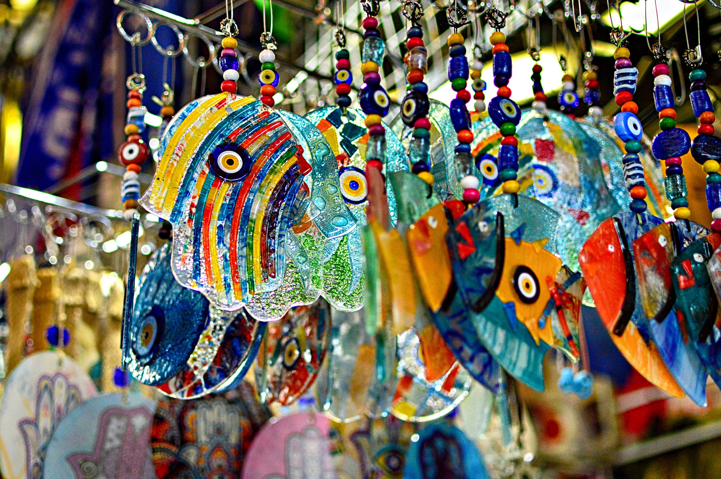 Colorful glass fish ornaments hanging in a display at a market or shop.